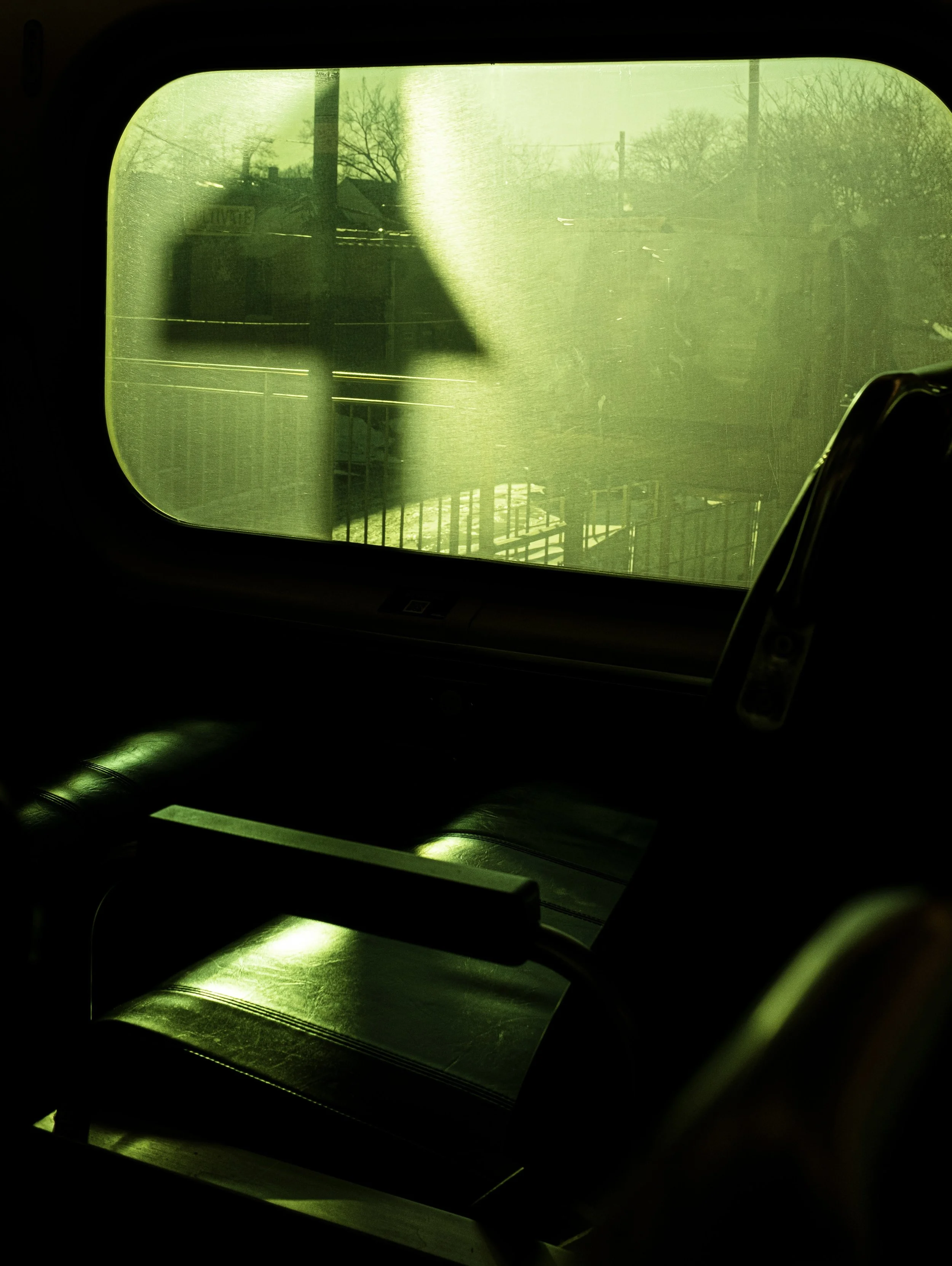 View through a dirty window with a yellow tint, showing silhouettes of trees and power lines outside on a clear day.