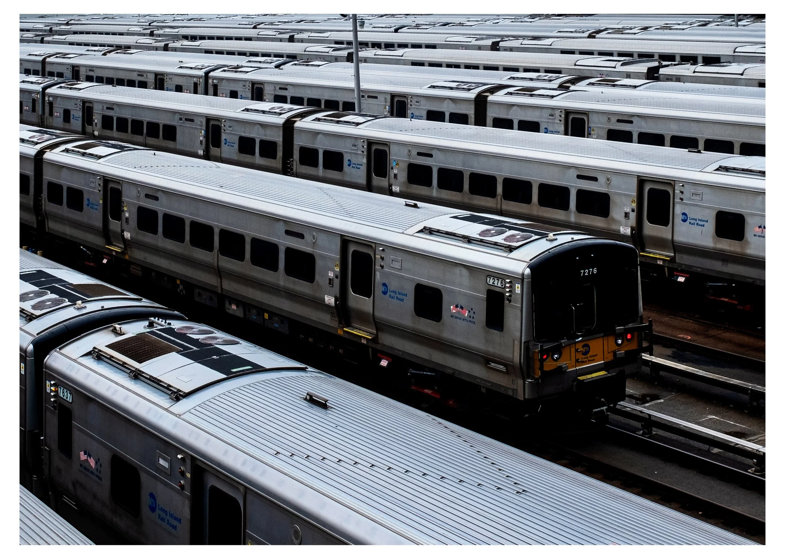 Multiple silver subway train cars parked in a train yard.