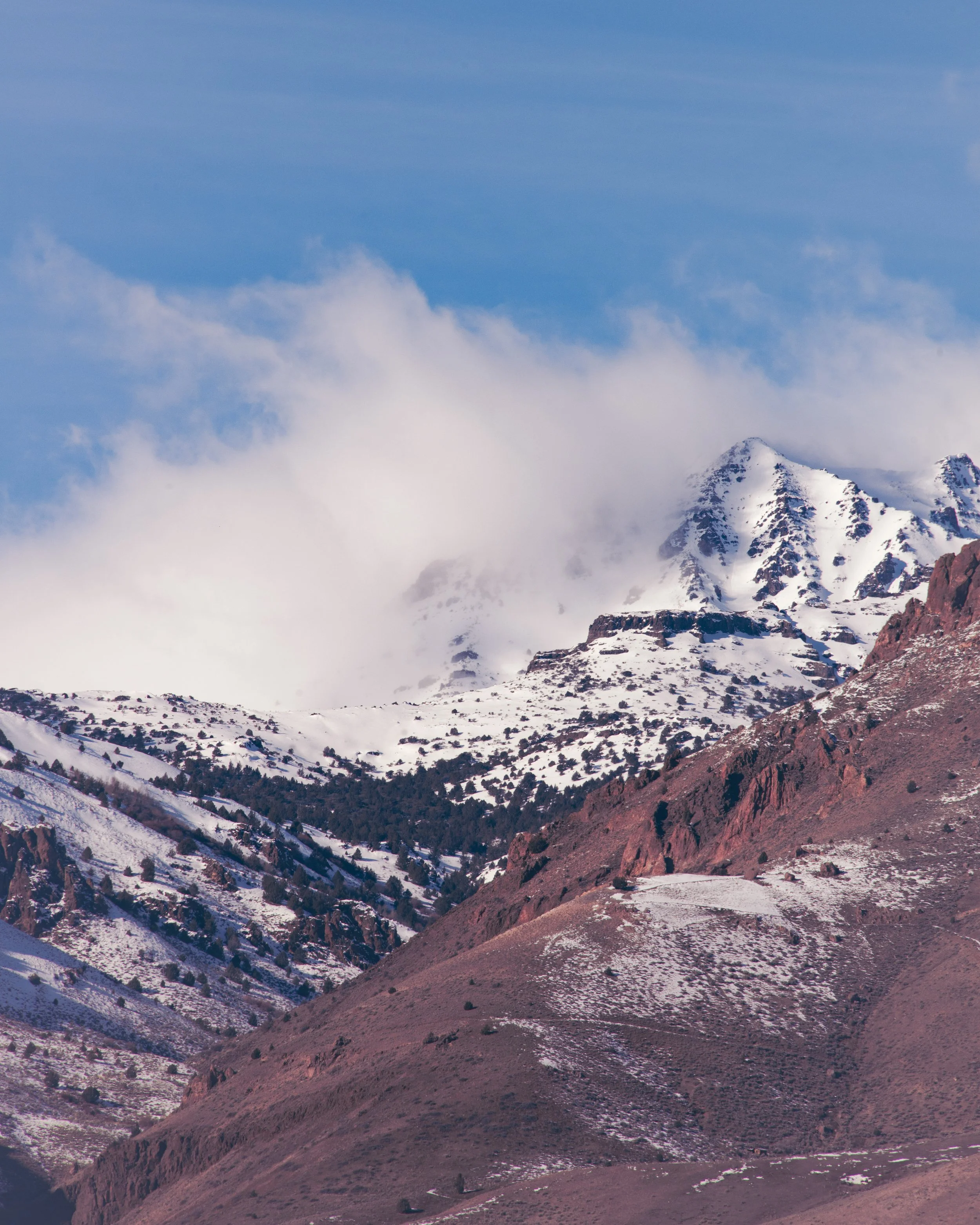 Snow-covered mountain peaks with a cloudy blue sky