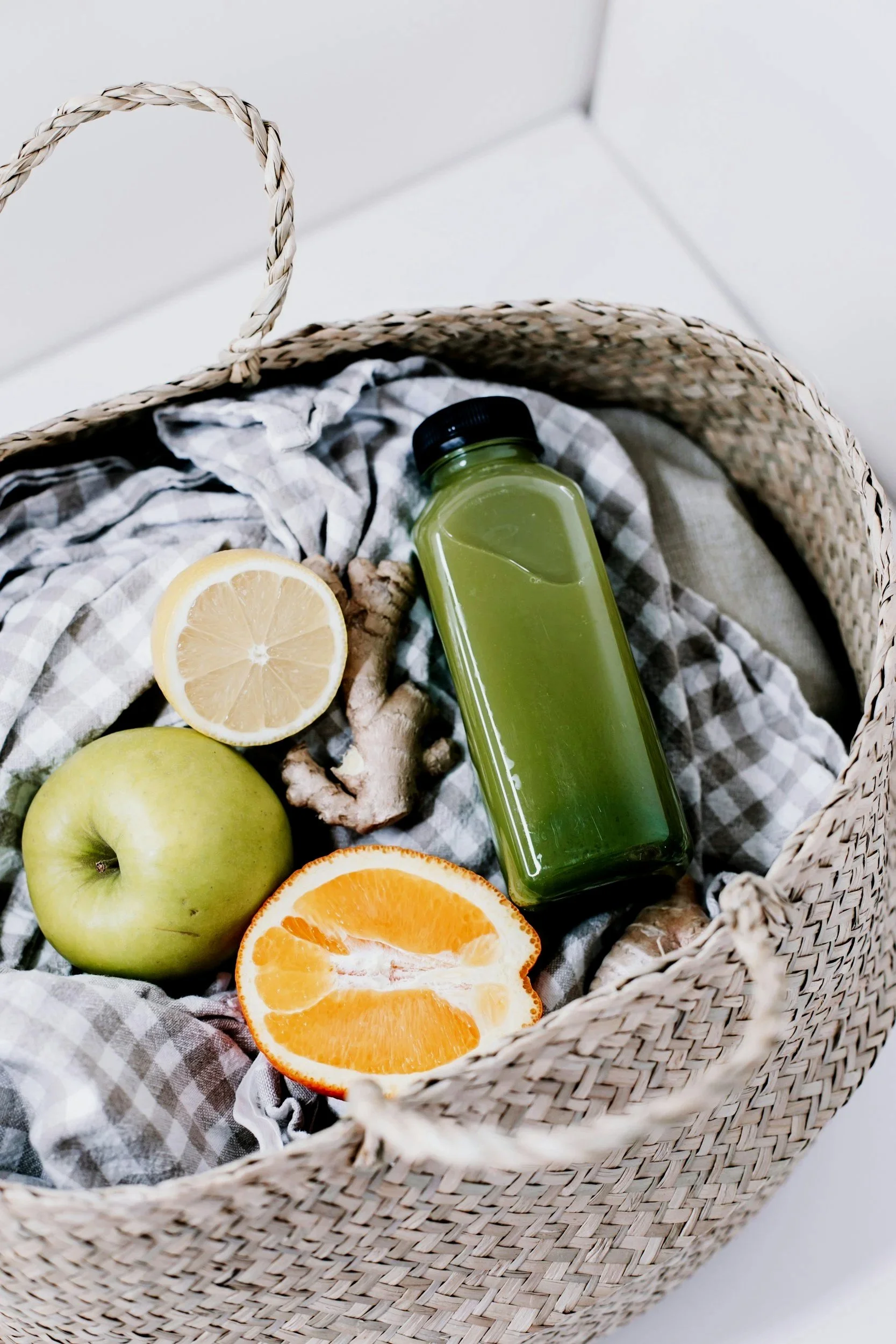 Green juice with apple, lemon and ginger arranged in a basket