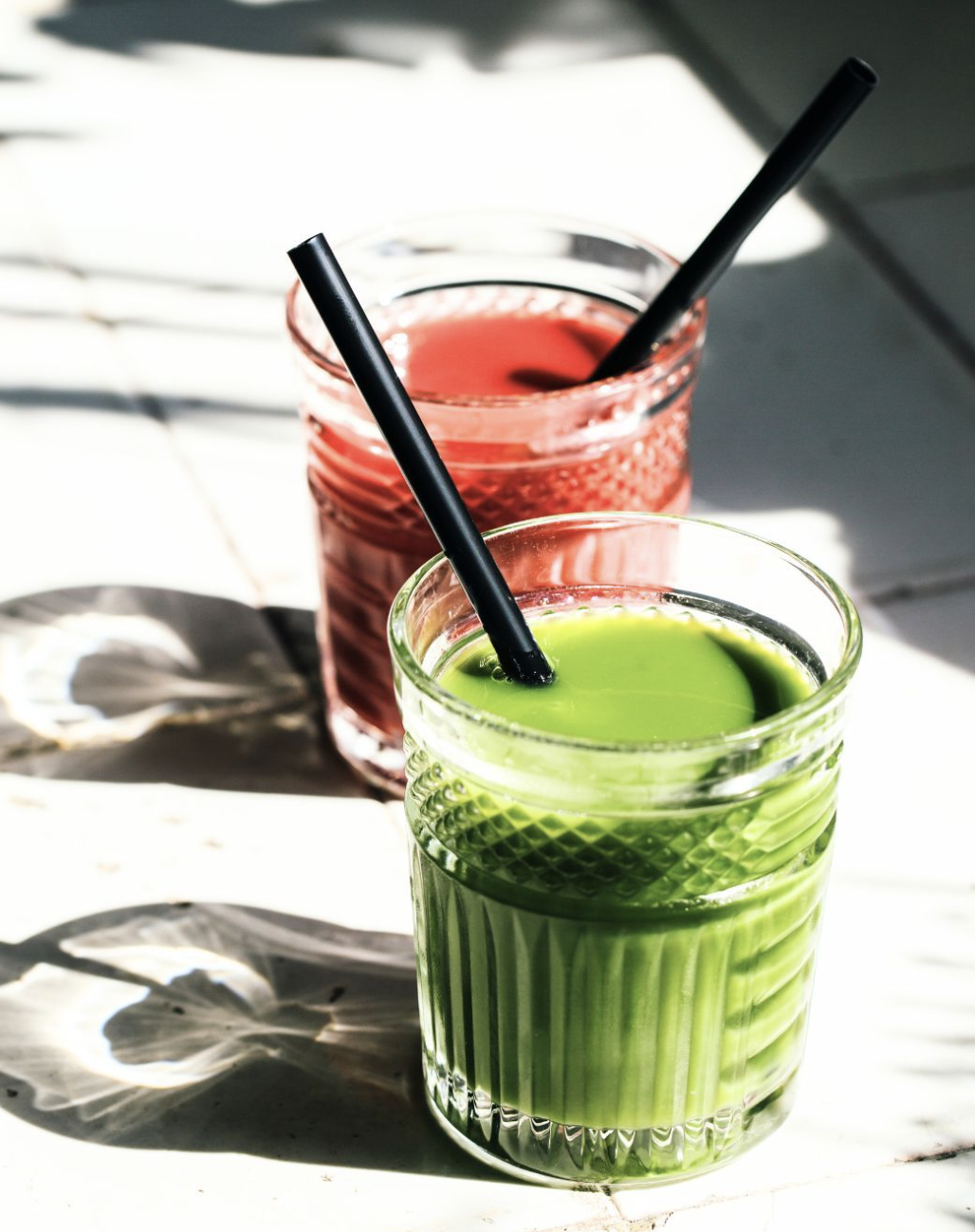 Fresh green juice and pink fruit juice in glasses
