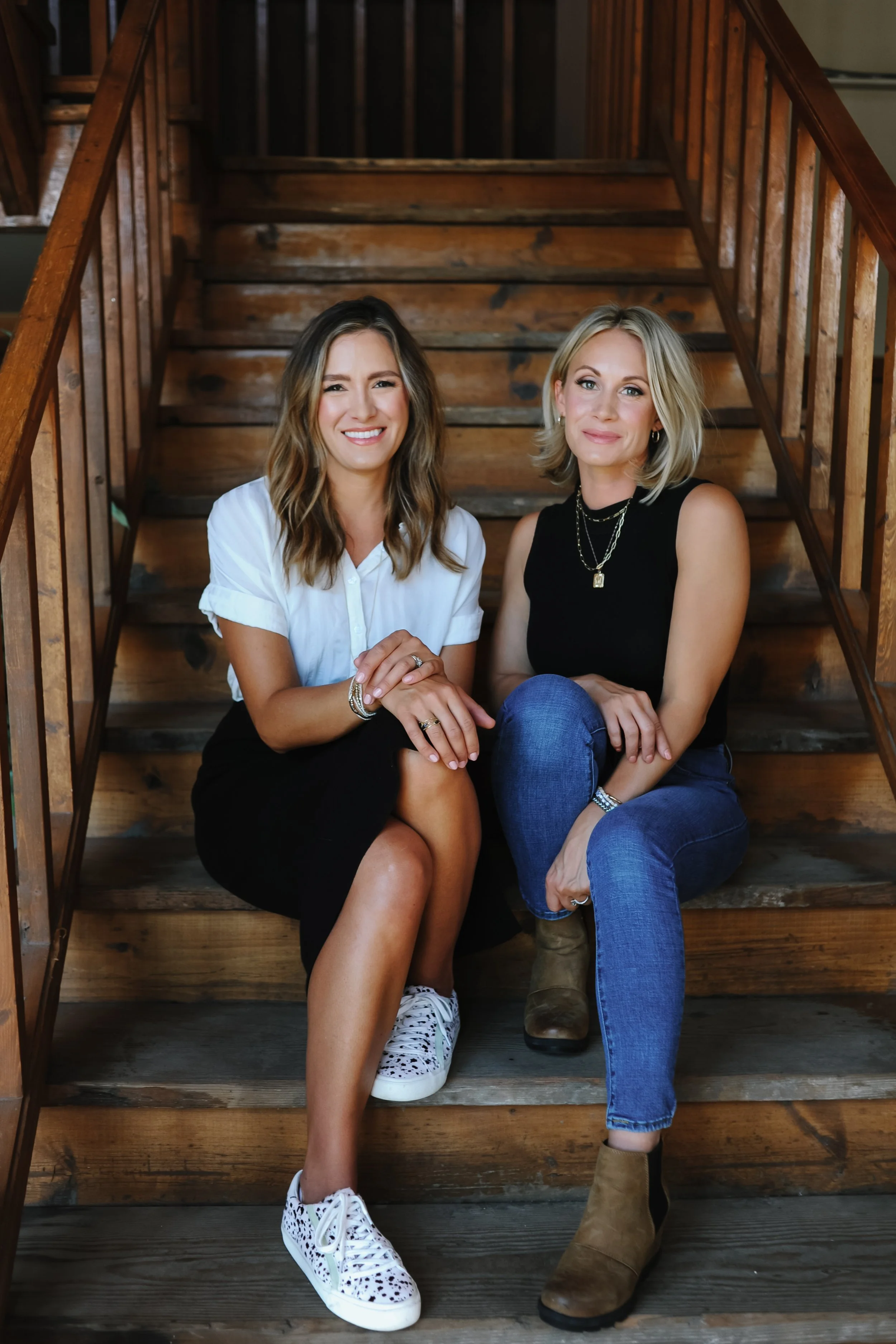 The Goodery co-founders Emily Iannazzo and Melissa Parkos sitting together on wooden stairs