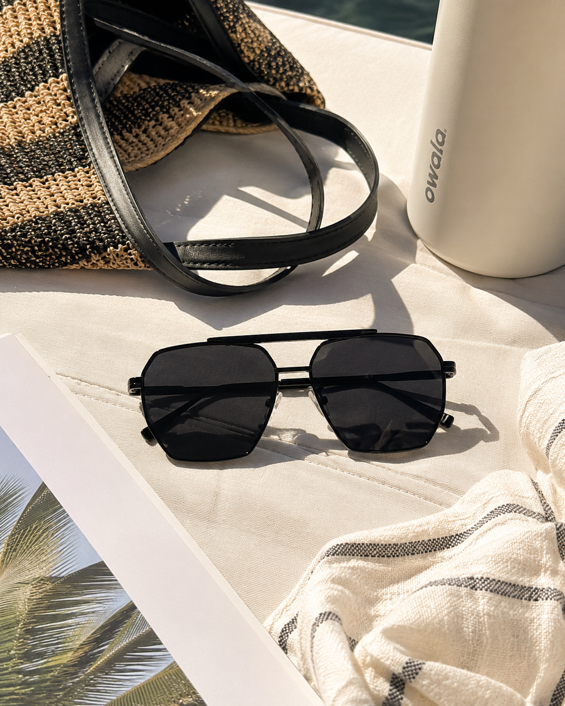 Black sunglasses beside a water bottle and casual outdoor essentials.