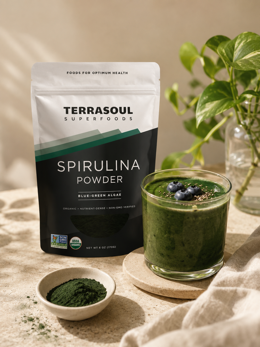 Organic spirulina powder beside a blended green smoothie.