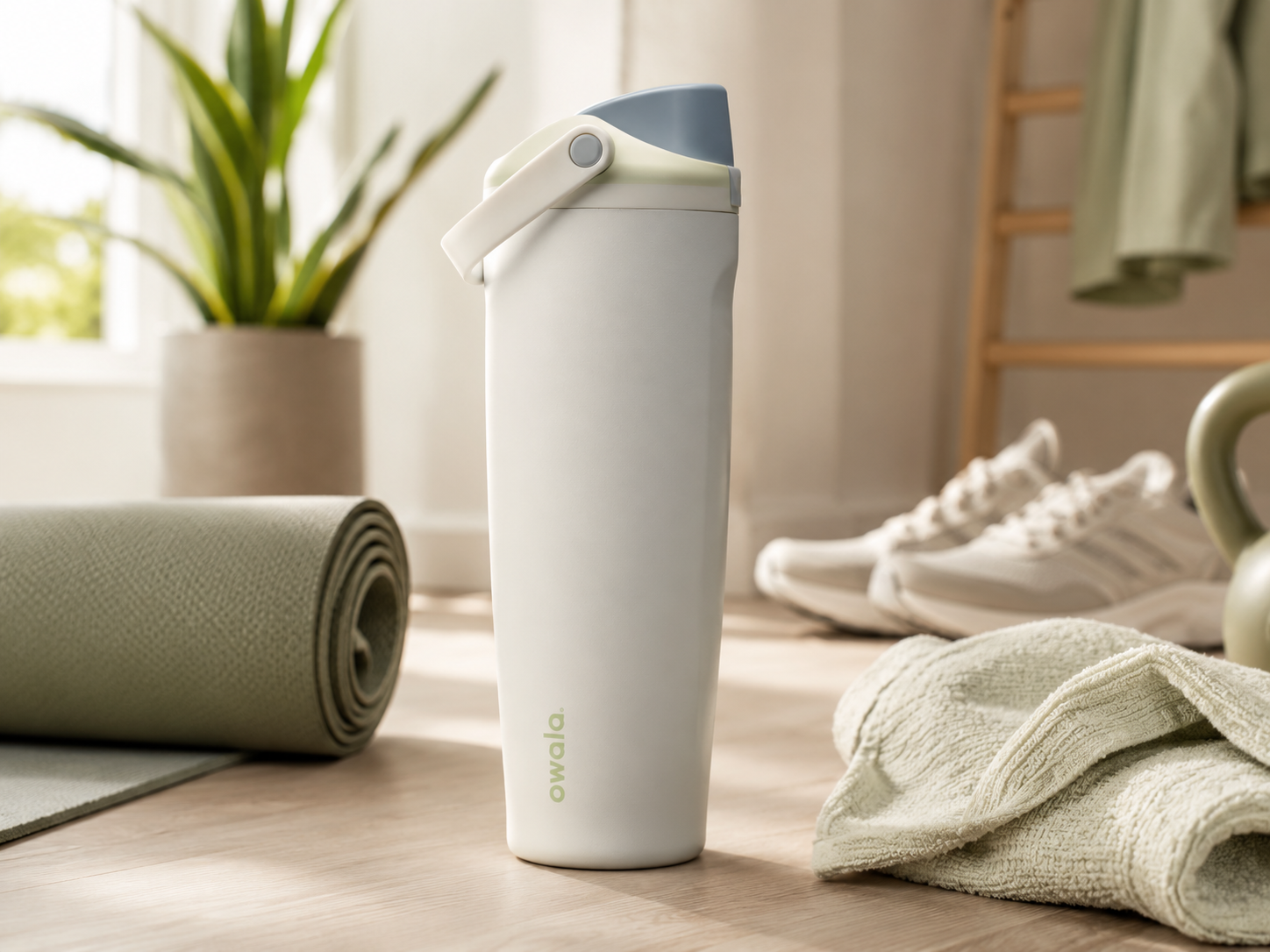 Owala water bottle beside a yoga mat, towel and sneakers.