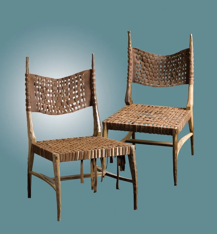 Two rustic wooden chairs with woven leather seats and backrests against a plain teal background.