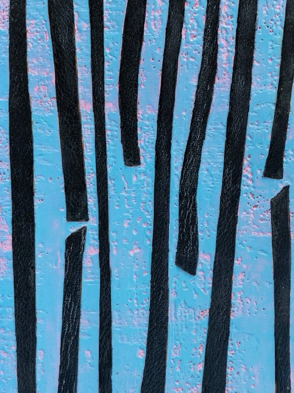 Close-up photo of textured black strips embedded in blue surface with pinkish accents.