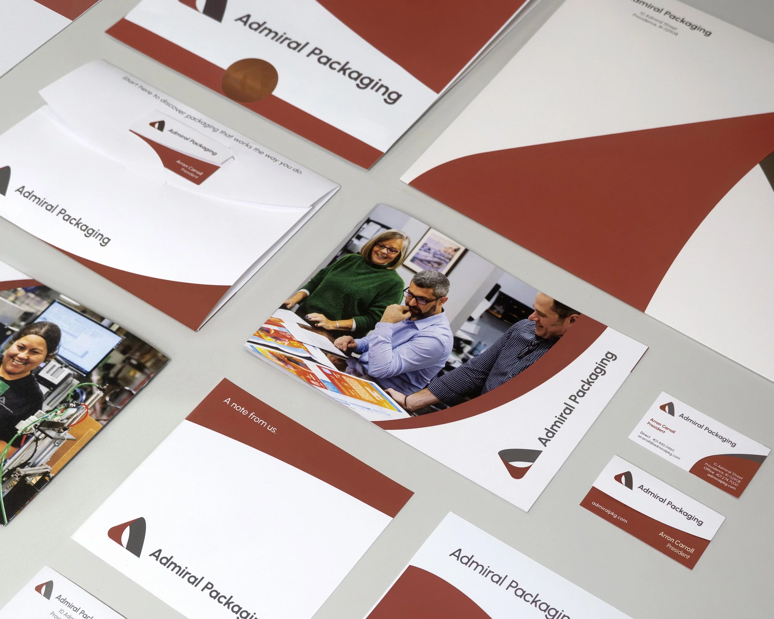 Close-up of free promotional brochures for Admiral Packaging with images of people at a meeting, showing smiling individuals and packaging equipment.