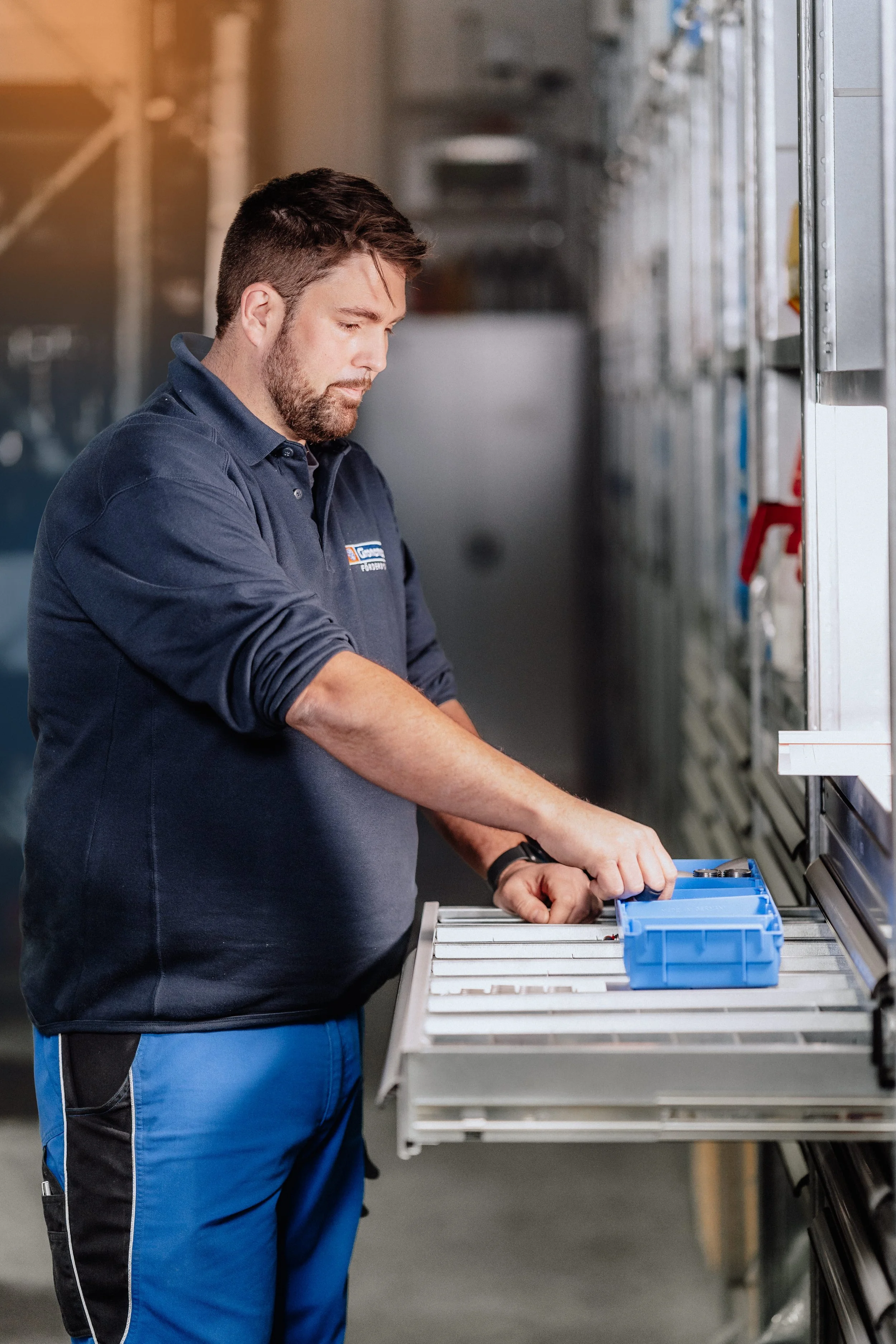 Mitarbeiter der Gronemeyer Maschinenfabrik entnimmt Kleinteile aus einem Industrieregal – authentische Unternehmensreportage und Corporate Fotografie in OWL