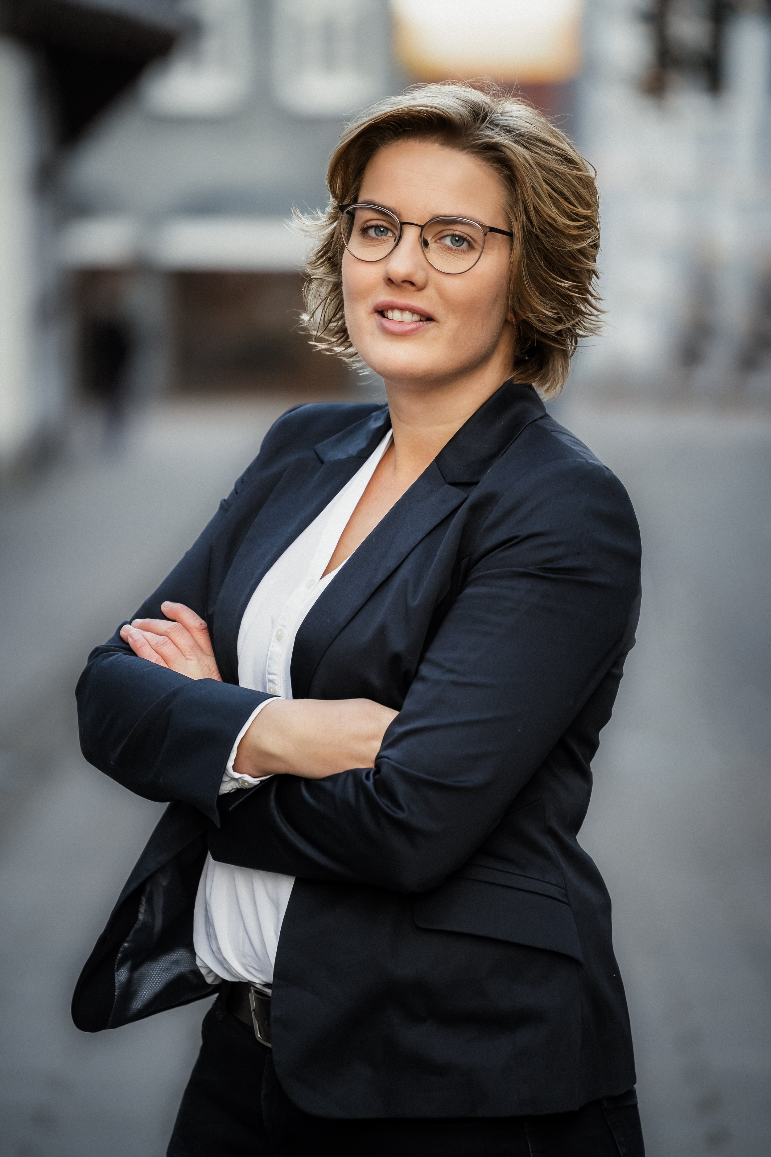Natürliches Business-Portrait einer Selbständigen mit Brille im dunklen Blazer, outdoor in der Altstadt – authentische Businessfotografie von Niklas Schulz Photography