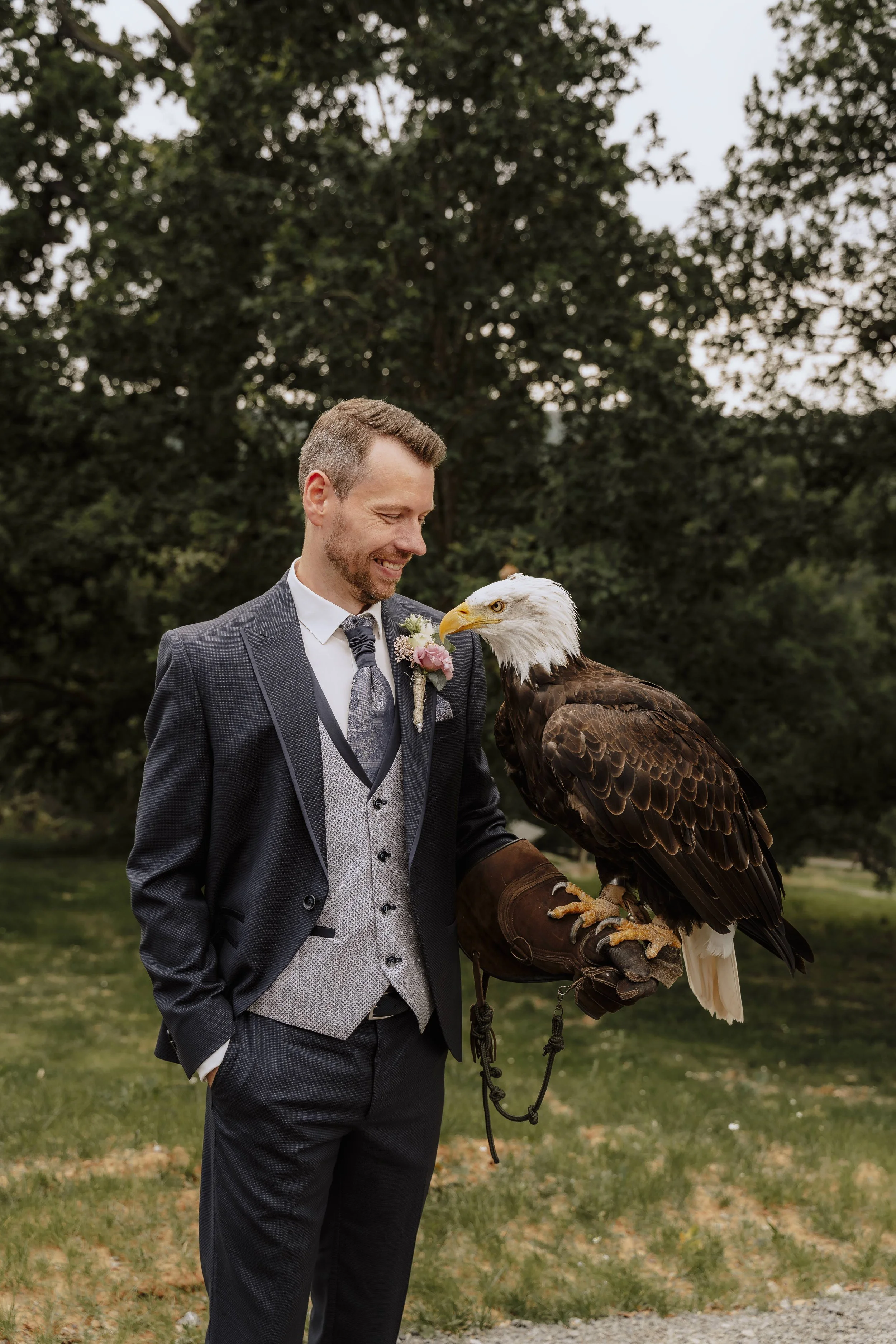Bräutigam mit Weißkopfseeadler auf dem Falknerhandschuh, liebevoller Blickkontakt – Hochzeitsfoto mit Adler