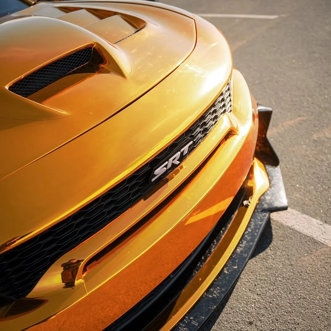Close-up of a yellow Chevrolet Camaro SS with black grille and front splitter on a parking lot.