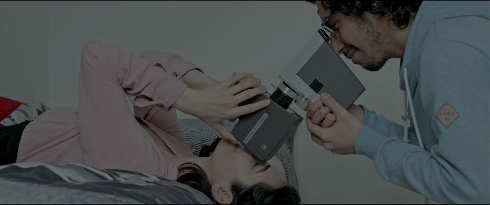 A person lying on a bed receiving a medical examination using a microscope from a healthcare professional.