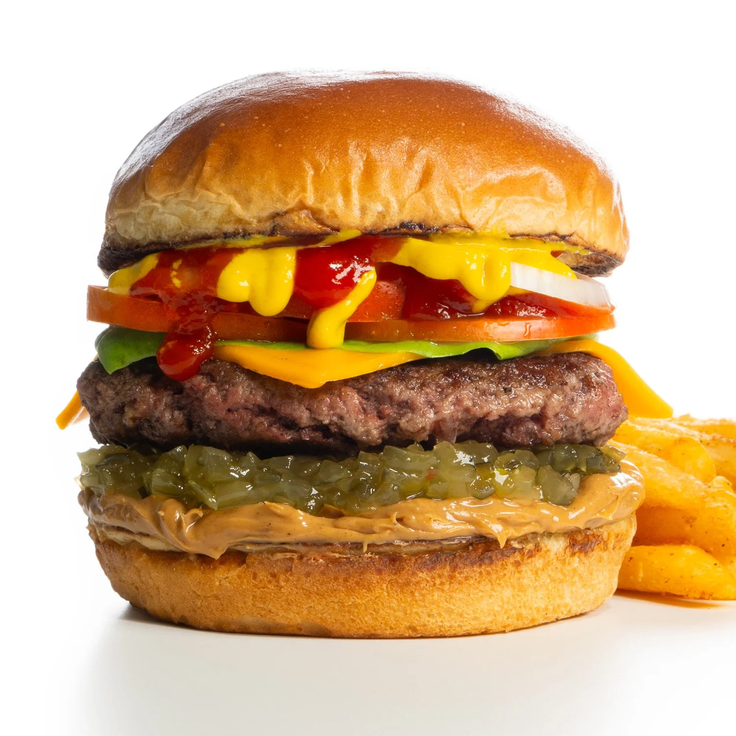 A close-up of a large cheeseburger with various toppings and a side of fries.