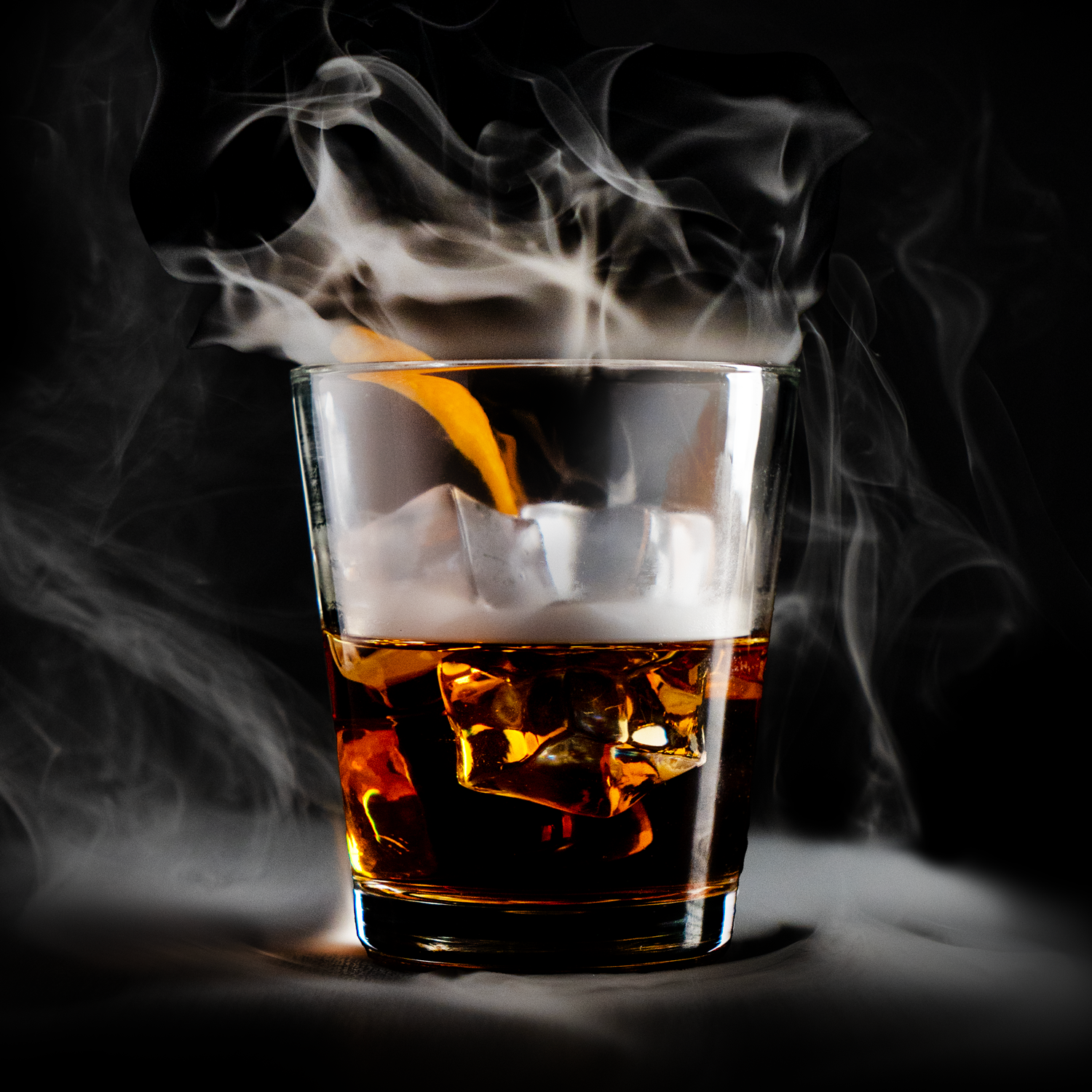 A glass of whiskey with ice and a lemon twist, with smoke swirling around it against a dark background.