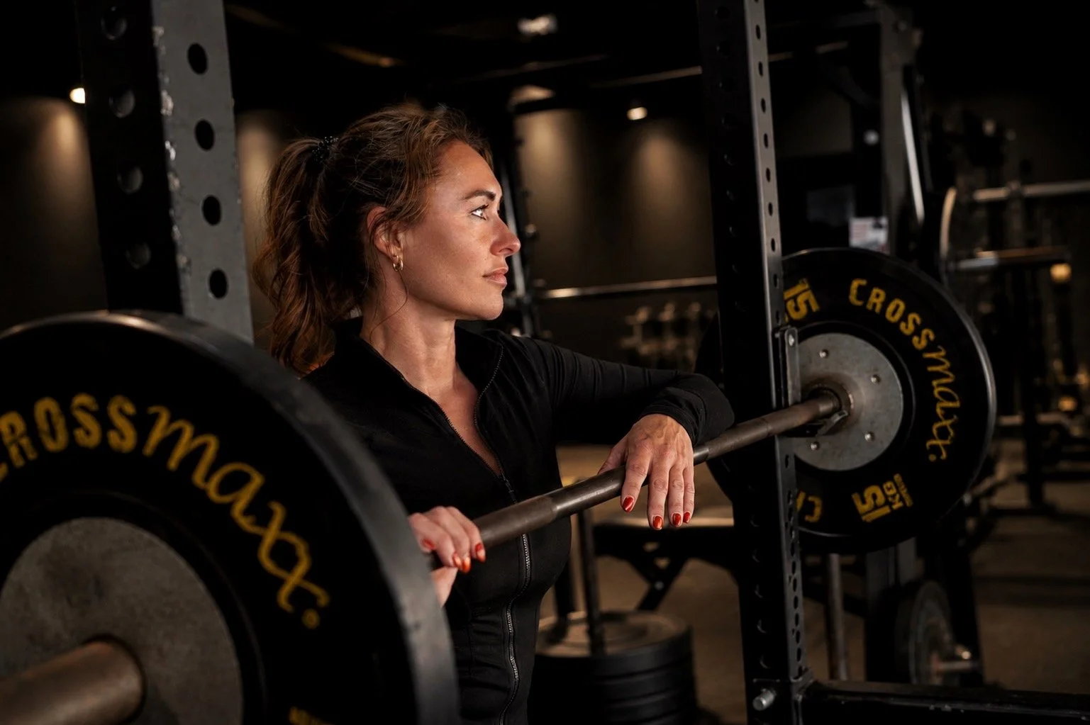 Vrouw in sportoutfit die een halterbank met gewichten gebruikt in een sportschool.