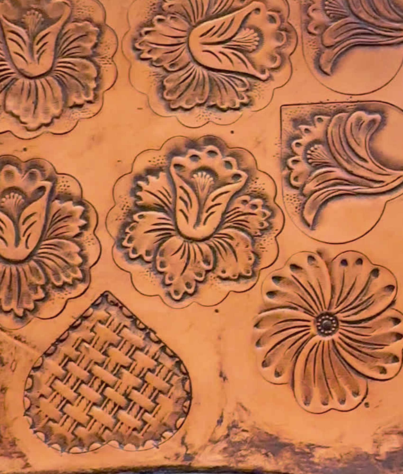 Close-up of carved floral patterns and a basket design on a wooden surface.