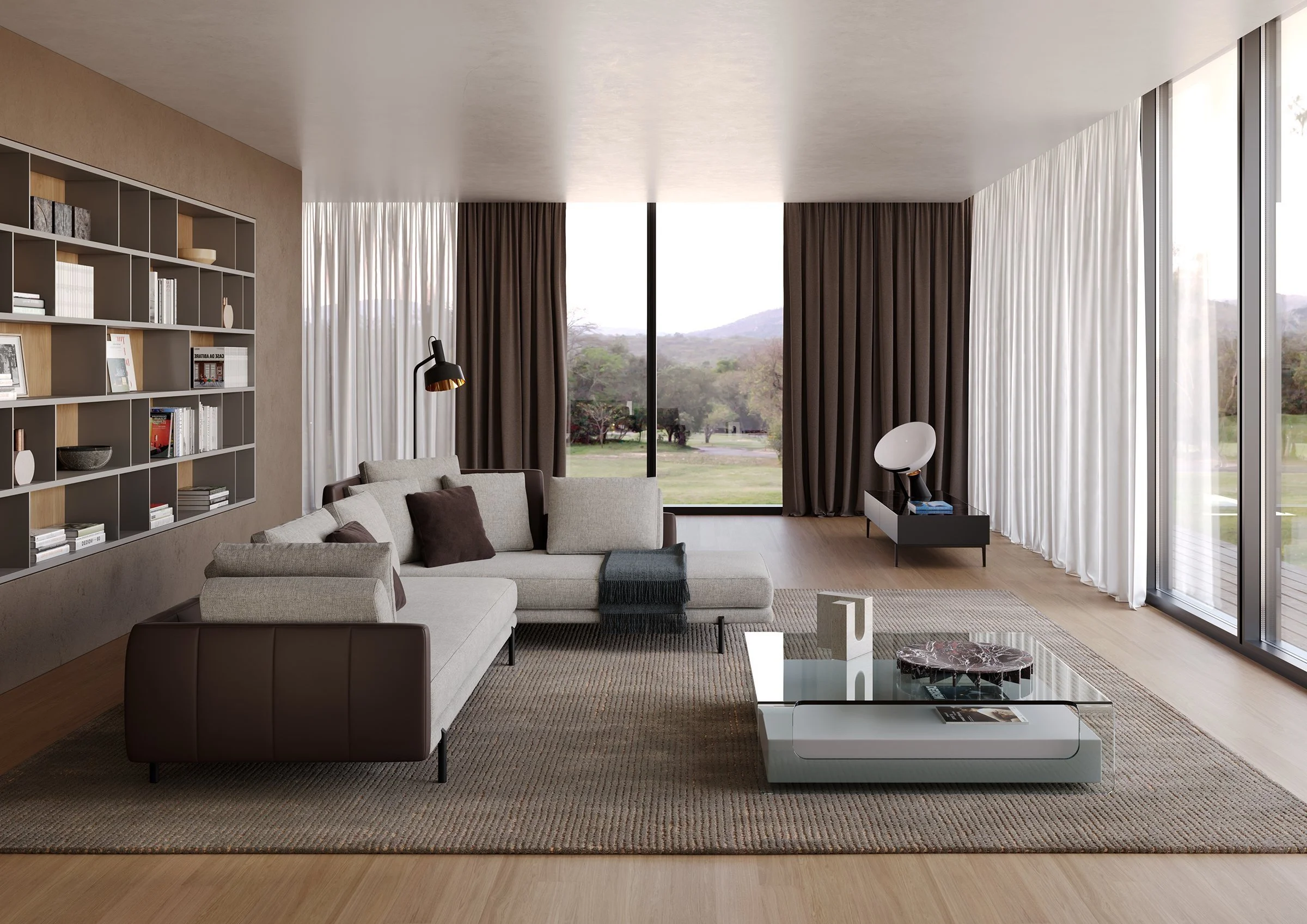 Modern living room with large windows, beige sofa with brown and gray cushions, white coffee table, black and marble side table, built-in bookshelf with decorative items and books, and scenic view of trees and hills outside.
