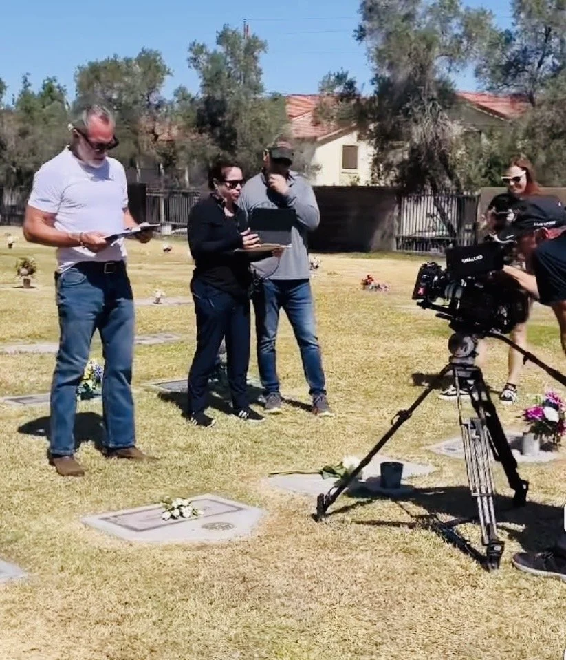 Group of people filming and reading at a cemetery.