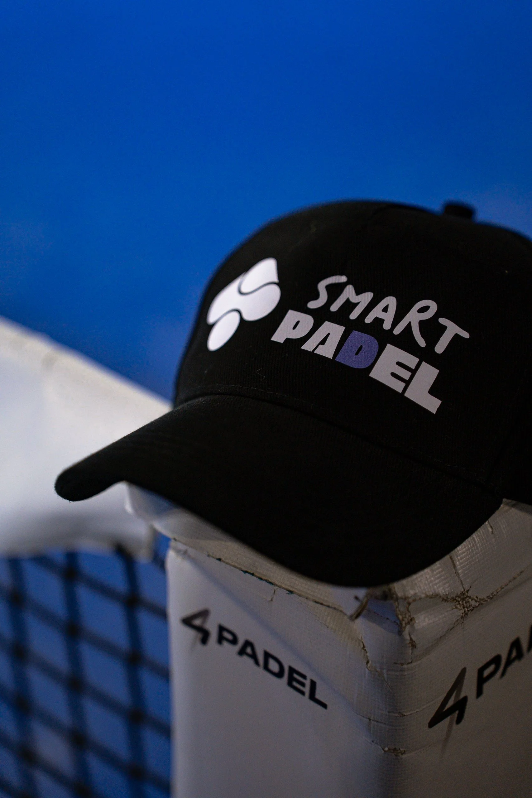 Casquette noire avec le logo de Smart Parade, posée sur une boîte zébrée
