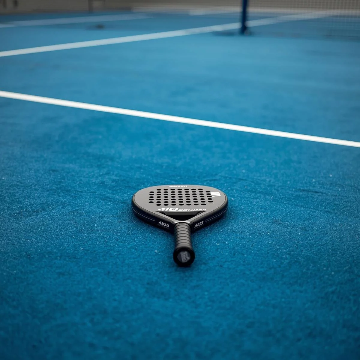 Une raquette de tennis sur un terrain de tennis en bleu.