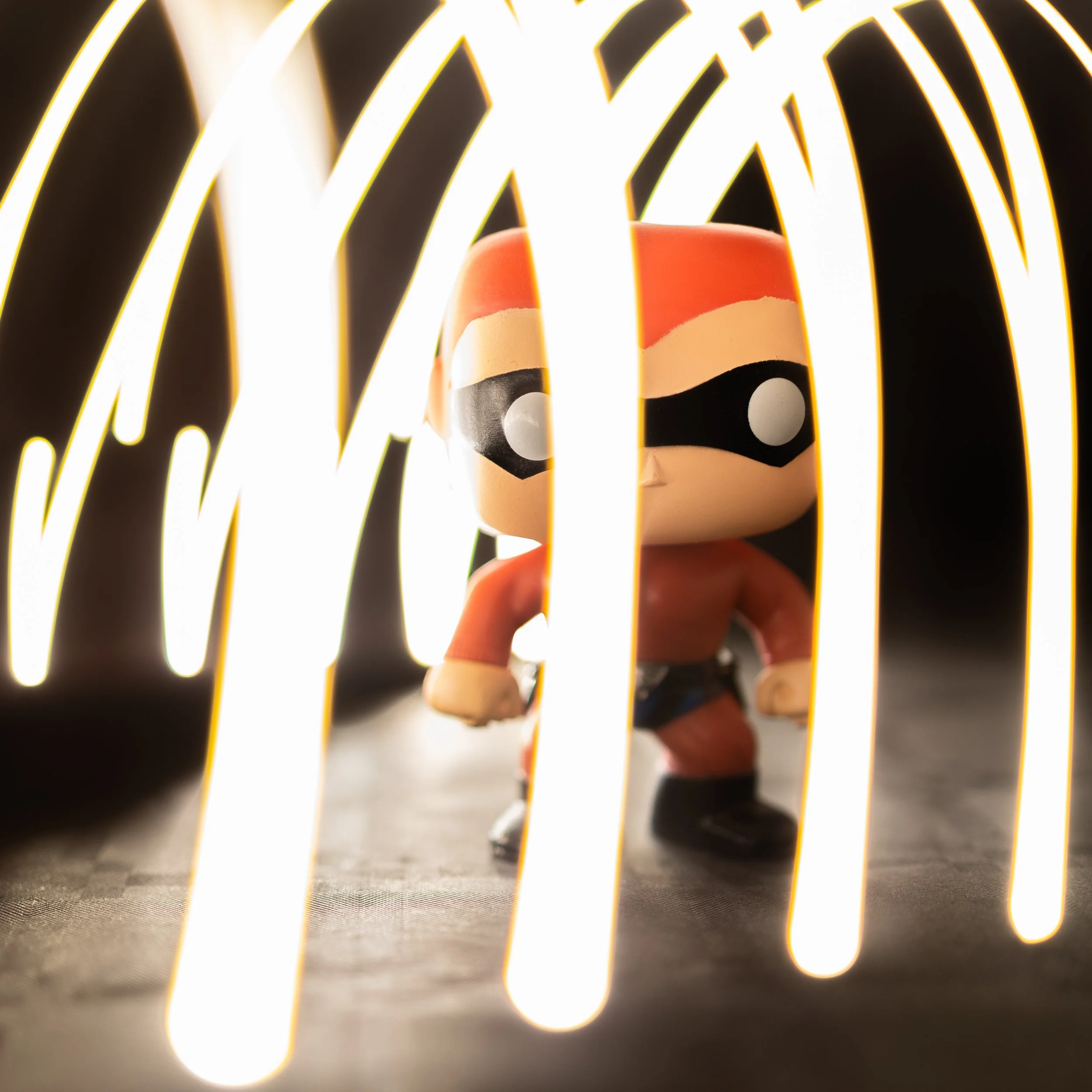 Close-up of a small figure dressed as a ladybug with black spots, viewed through yellowish glowing bars in the foreground.