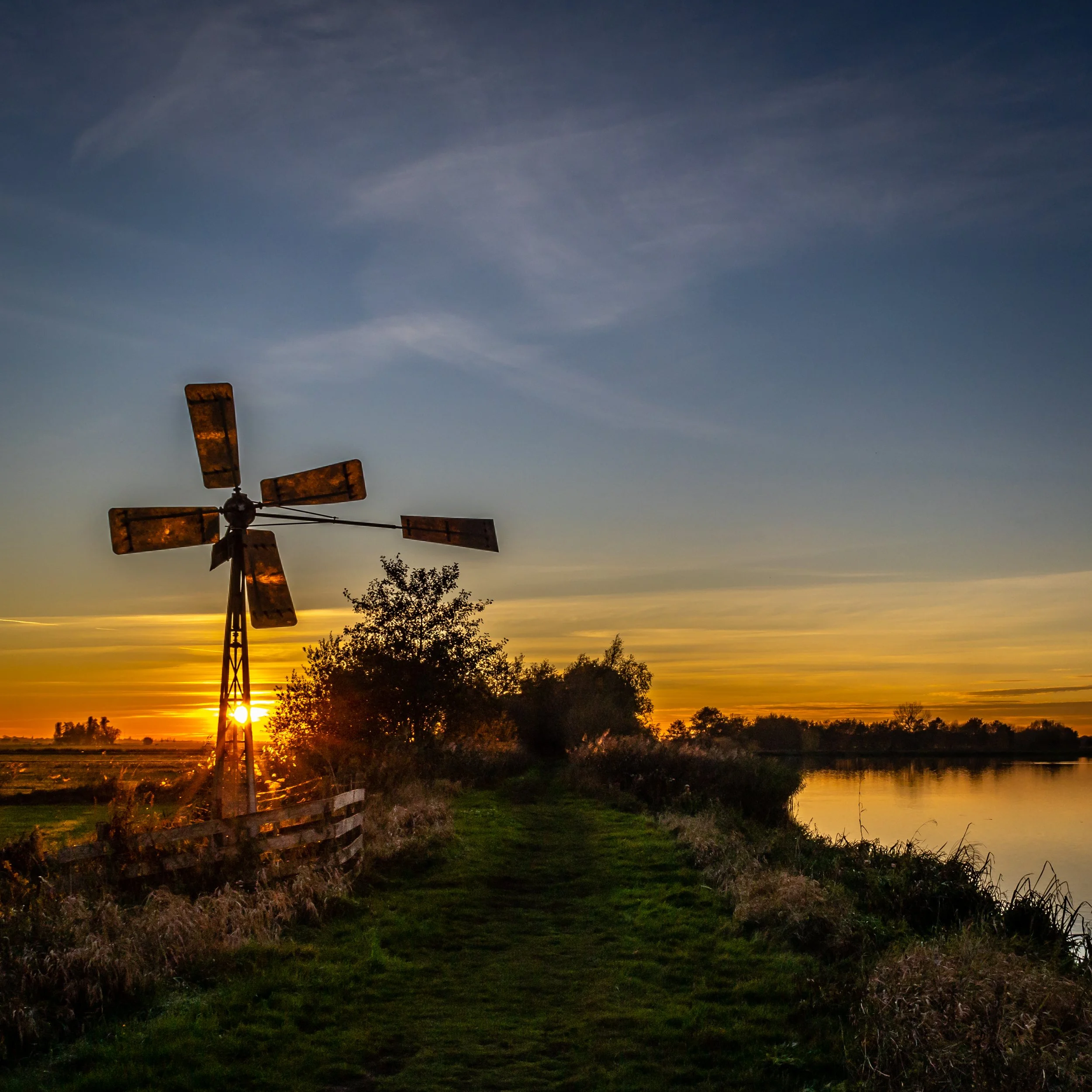 Dutch windmill with the setting sun shining through the blades — Blokland, Montfoort — Netherlands — by ROEL | WILLEM