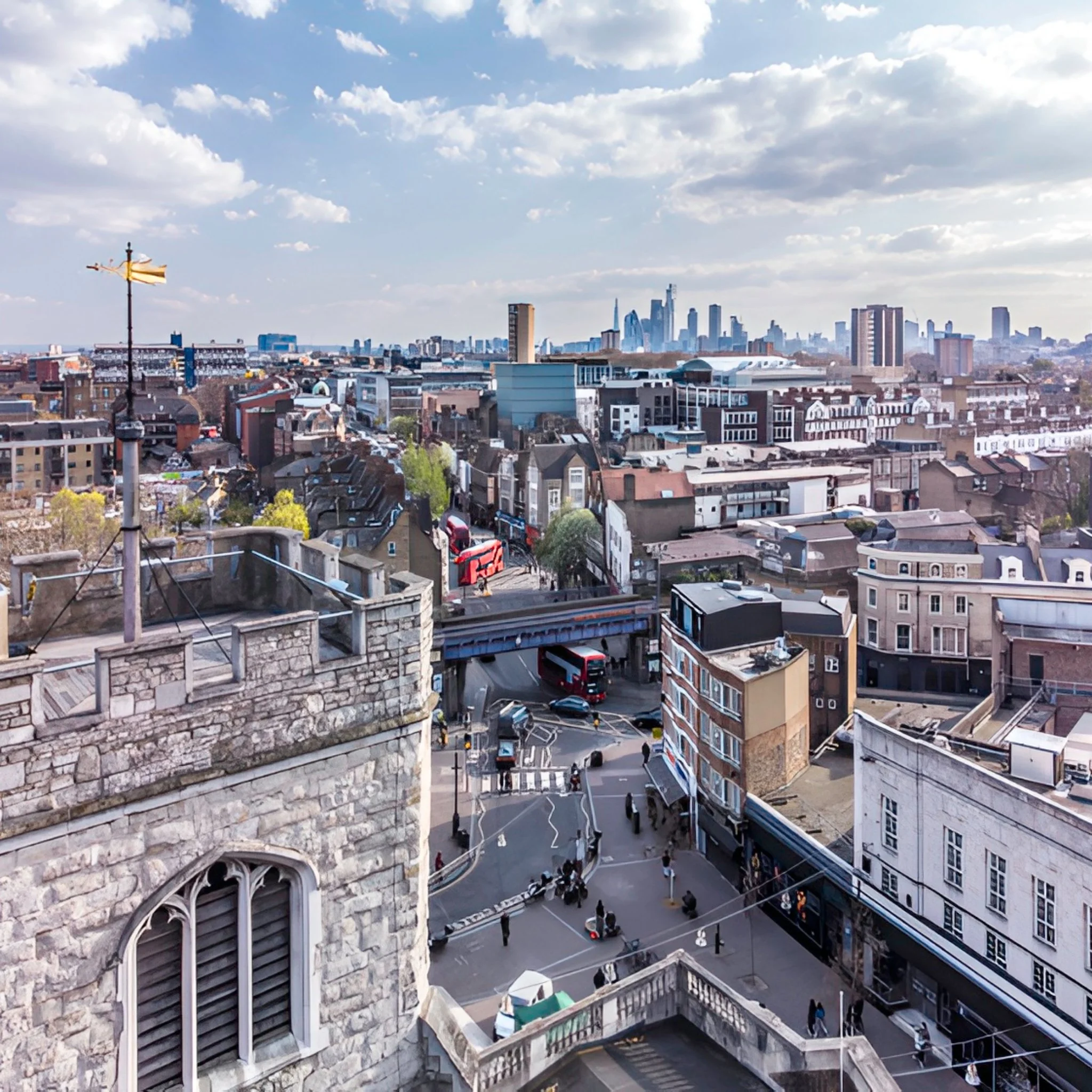 A cityscape view from a rooftop showing historic stone building with arched windows in the foreground and modern skyscrapers in the background under a partly cloudy sky.