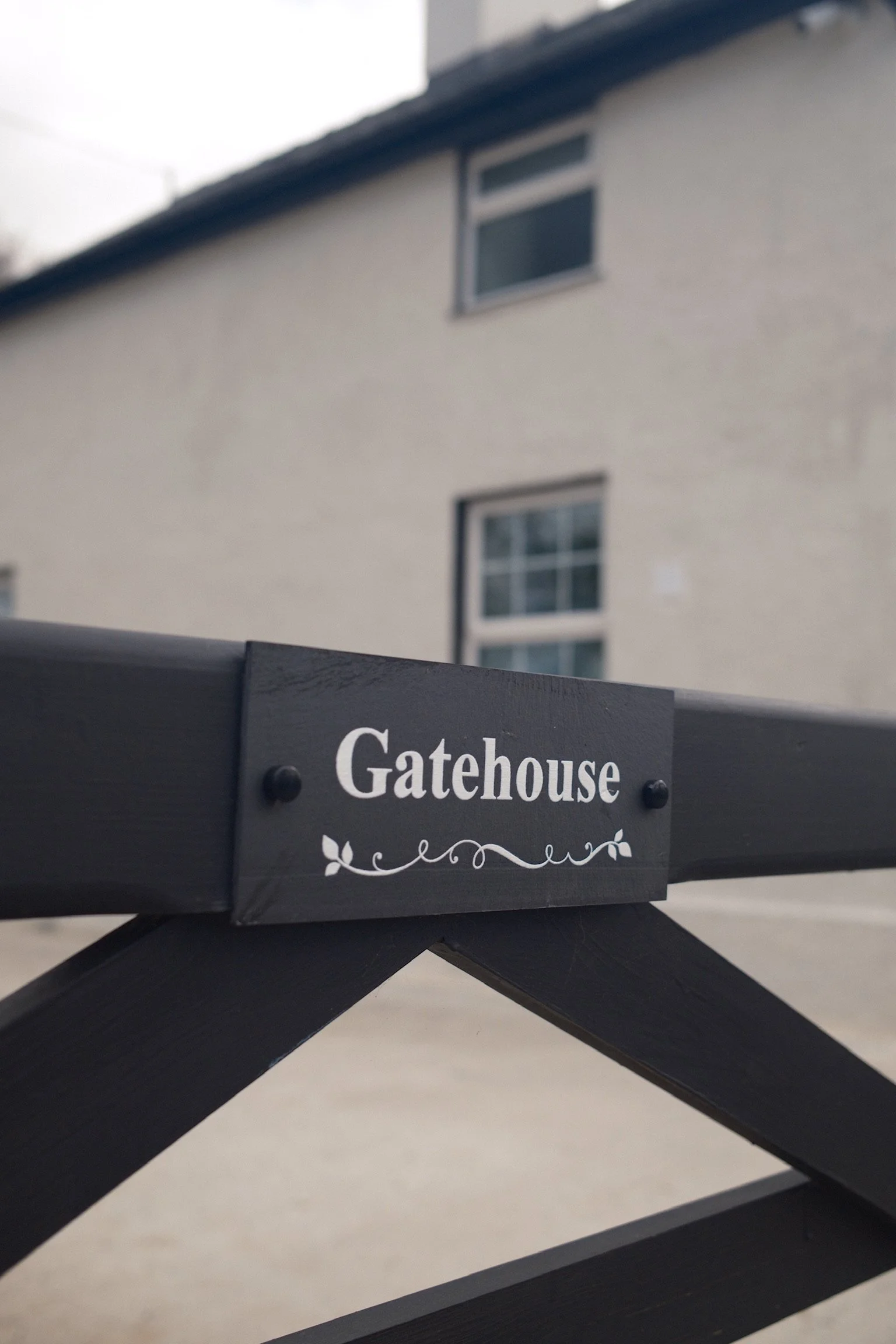 Close-up of a black sign on a bench that reads 'Gatehouse' in white text with decorative elements.