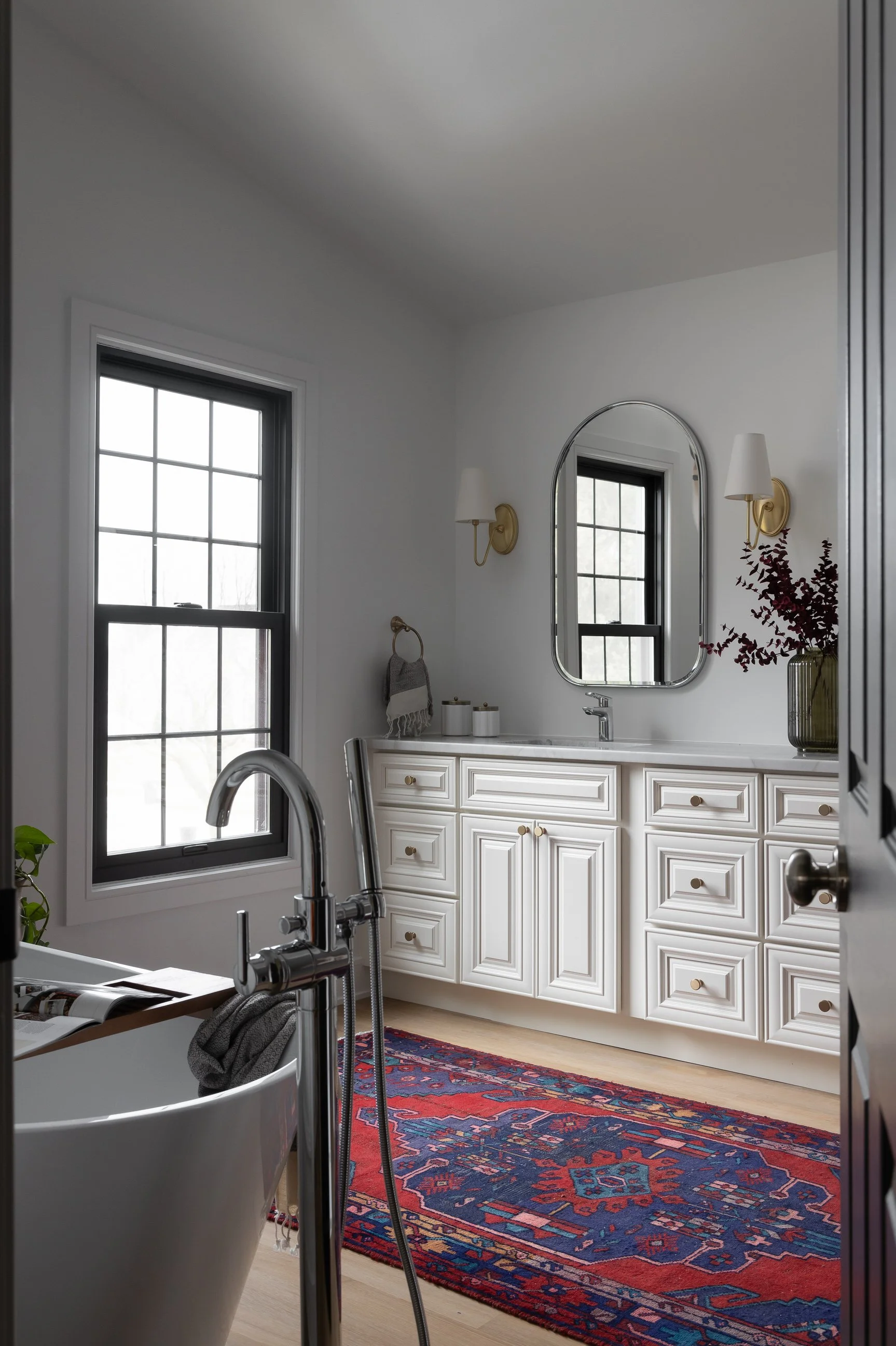 floating tub with white vanity and bold red and blue rug