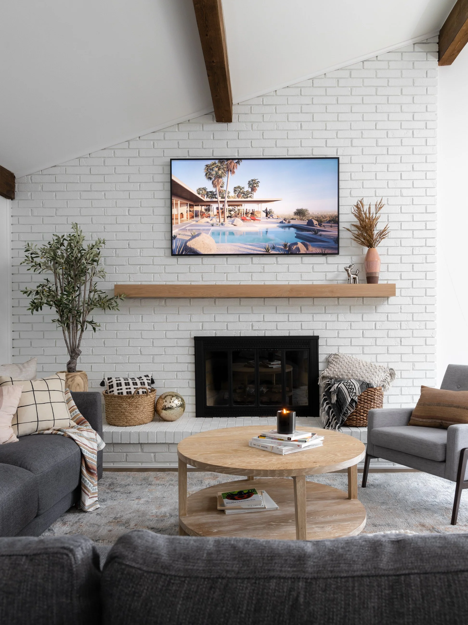 White brick fireplace with large TV and floating shelf