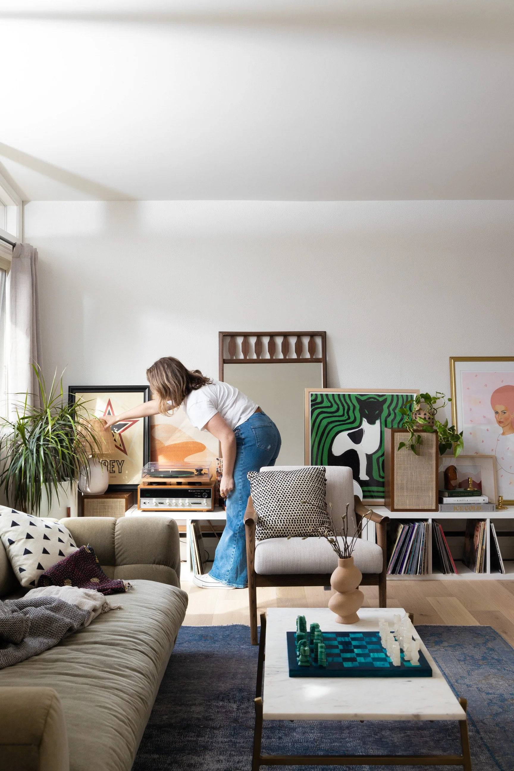 Interior designer looking over a gallery wall with unique artwork and textural elements