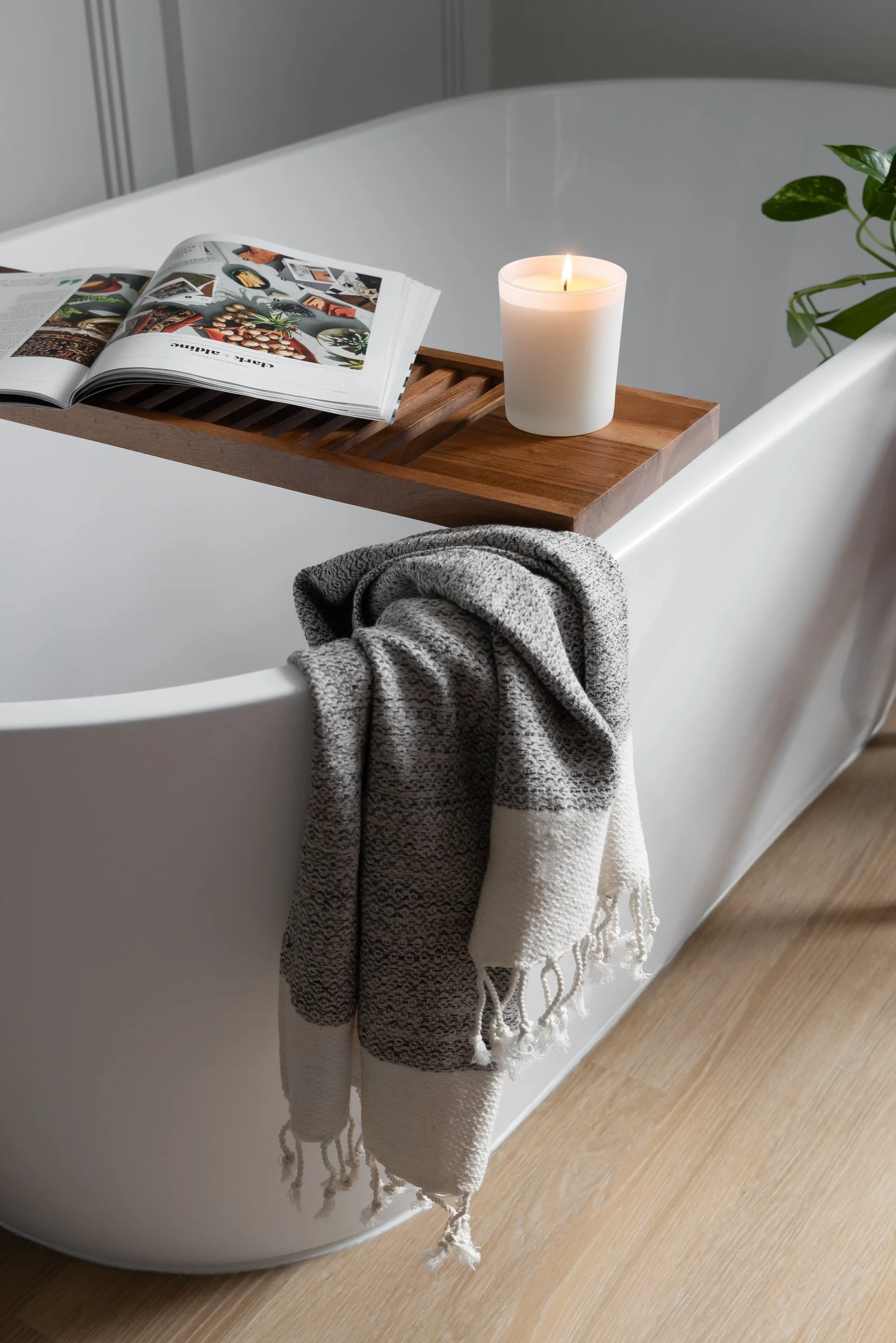 tranquil bathroom space with wooden shelf, candle and magazine