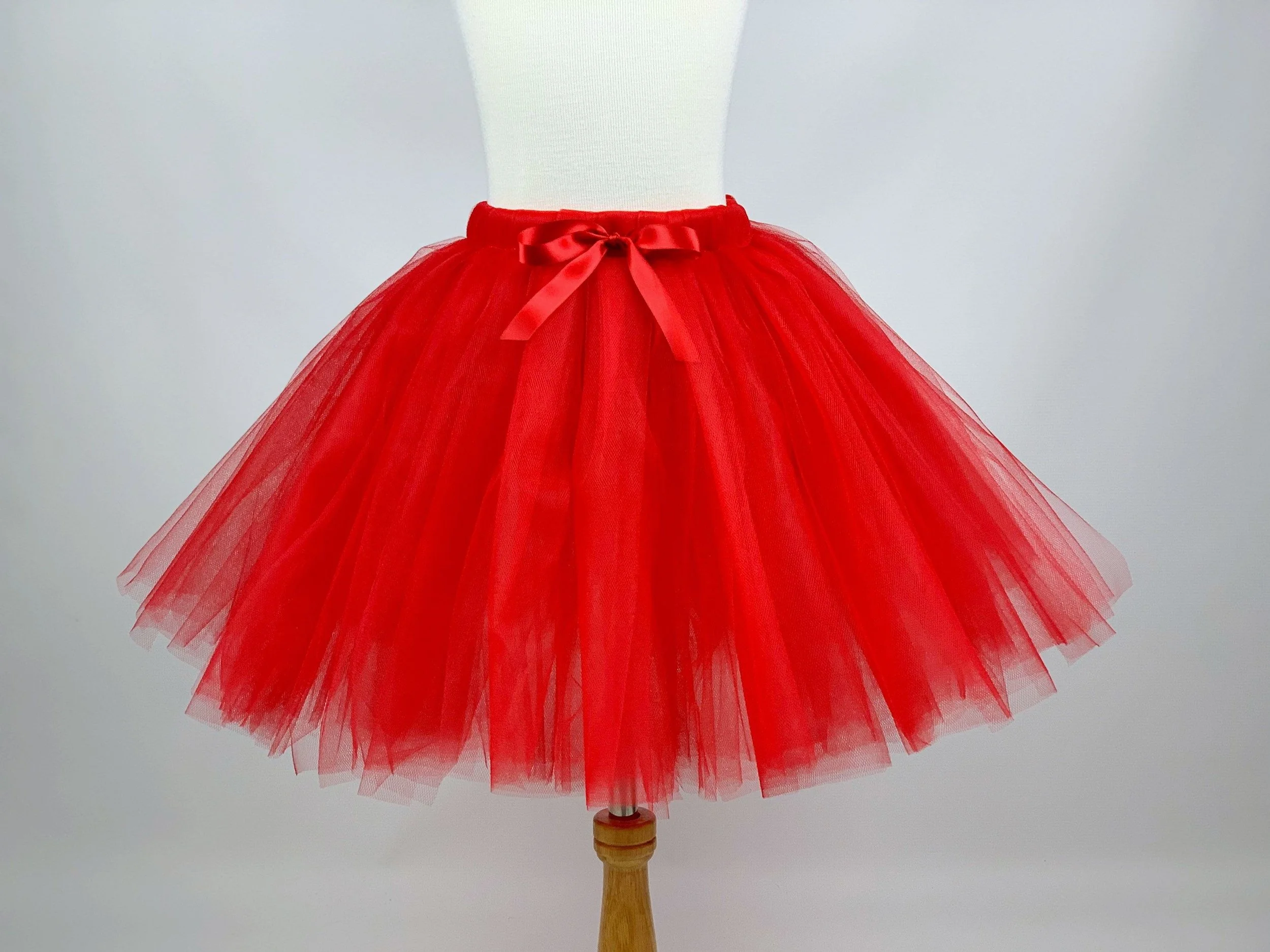 Red tutu skirt on a display stand with a white mannequin torso, against a plain white background.