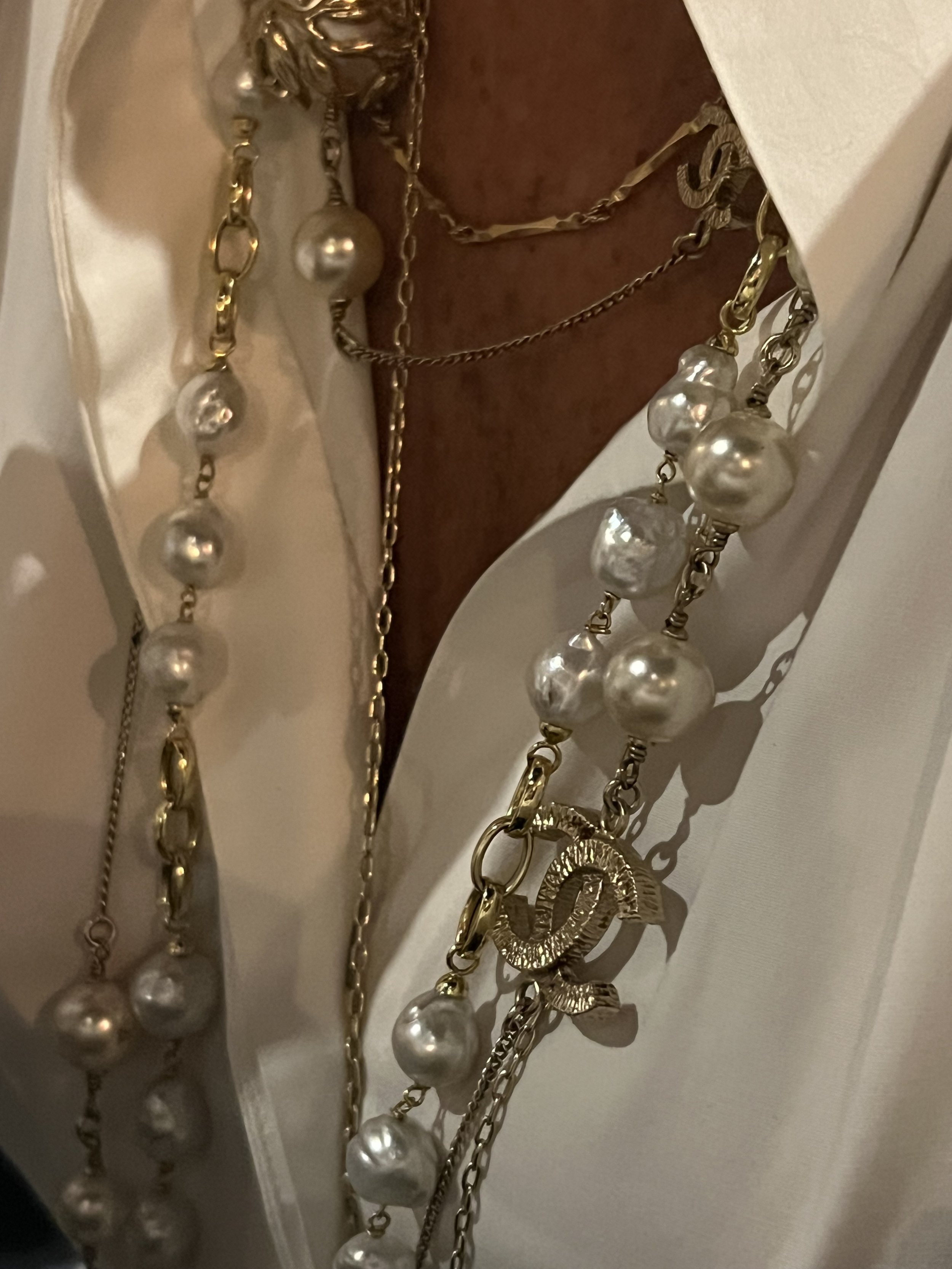 Close-up of various silver and gold jewelry, including necklaces and chains, hanging on a display.