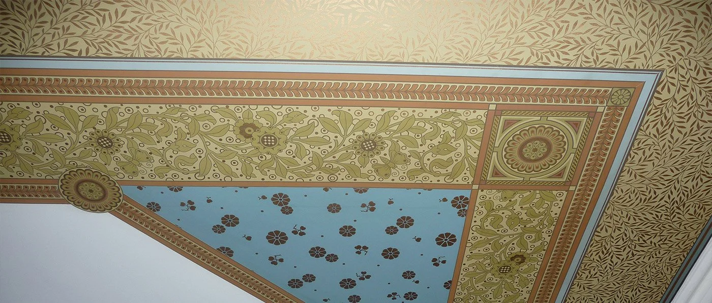 Ornate ceiling with intricate floral and geometric patterns in shades of beige, green, blue, and brown.