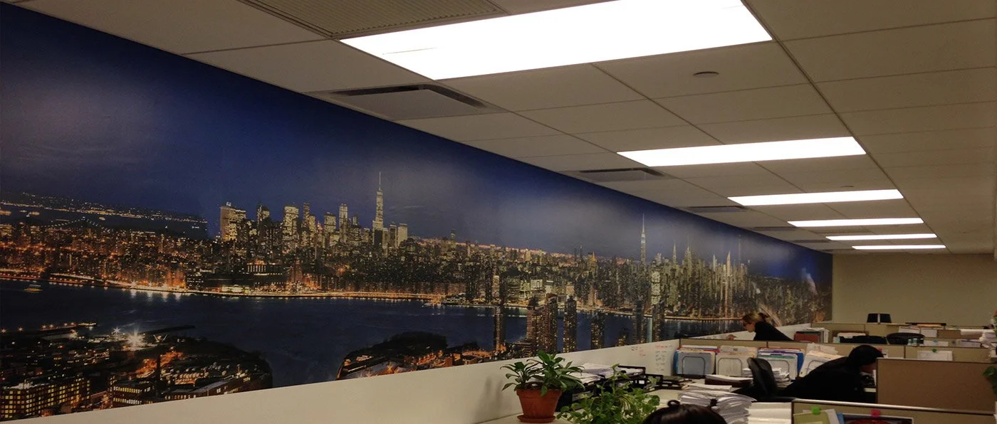 Office workspace with a panoramic mural of a city skyline at night, featuring skyscrapers and river.