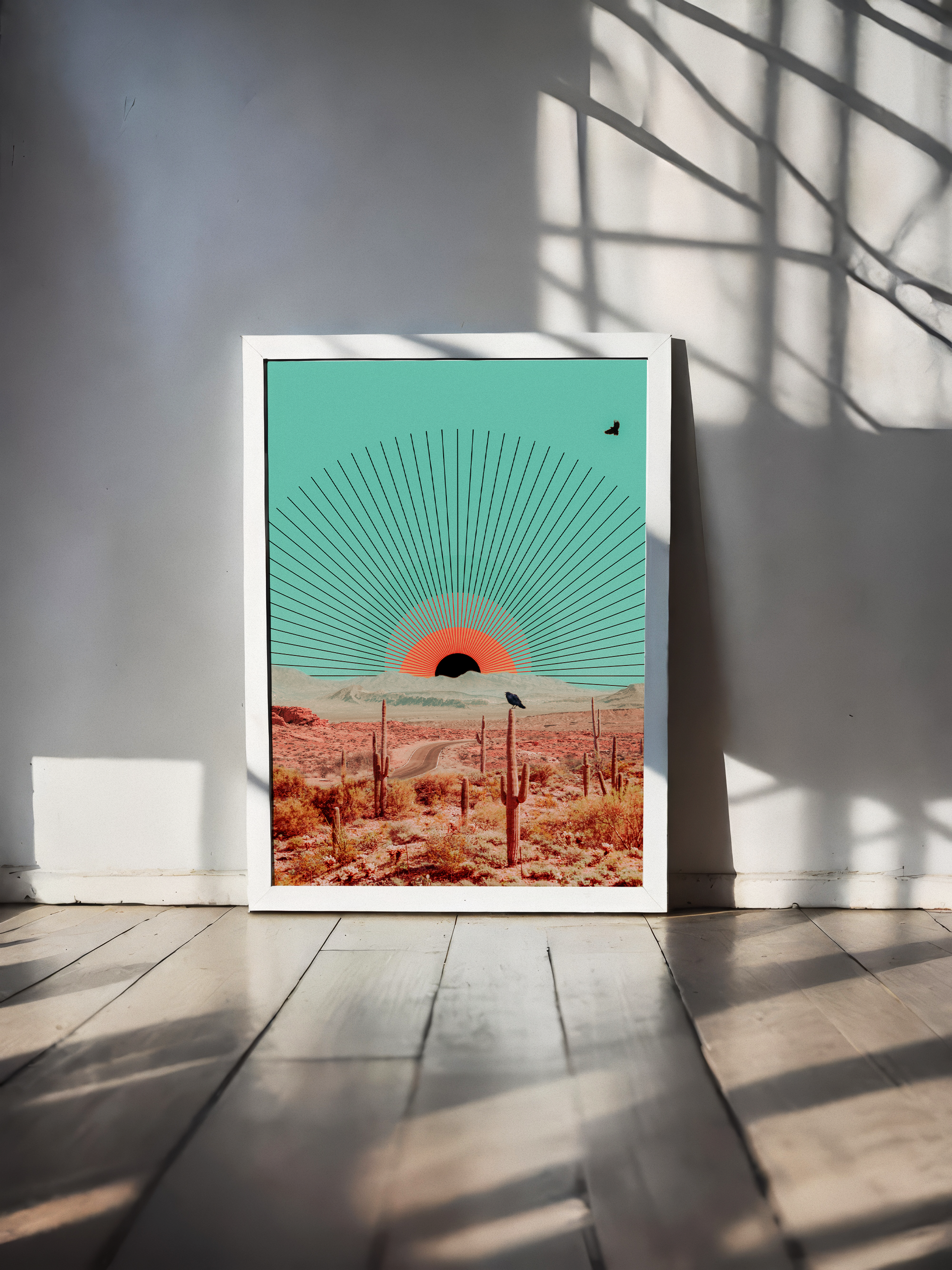 A framed art print of a desert scene with a setting or rising sun, cacti, and a single bird, placed on a white wooden floor and casting shadows through window blinds.