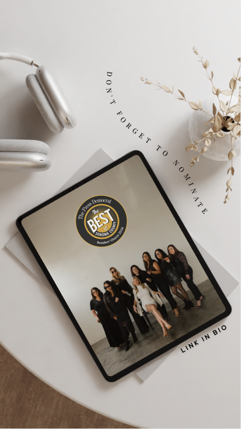 An iPad displaying a group photo of seven women standing together, dressed in black and white outfits, on a light-colored background. The iPad has a sticker that reads "Best of" with additional text. The scene includes a pair of headphones, a white book or notebook, and a vase with dried flowers on a round white table. There's also a decorative phrase on the table that says, "Don't forget to nominate," and a note at the bottom right that says, "Link in bio."