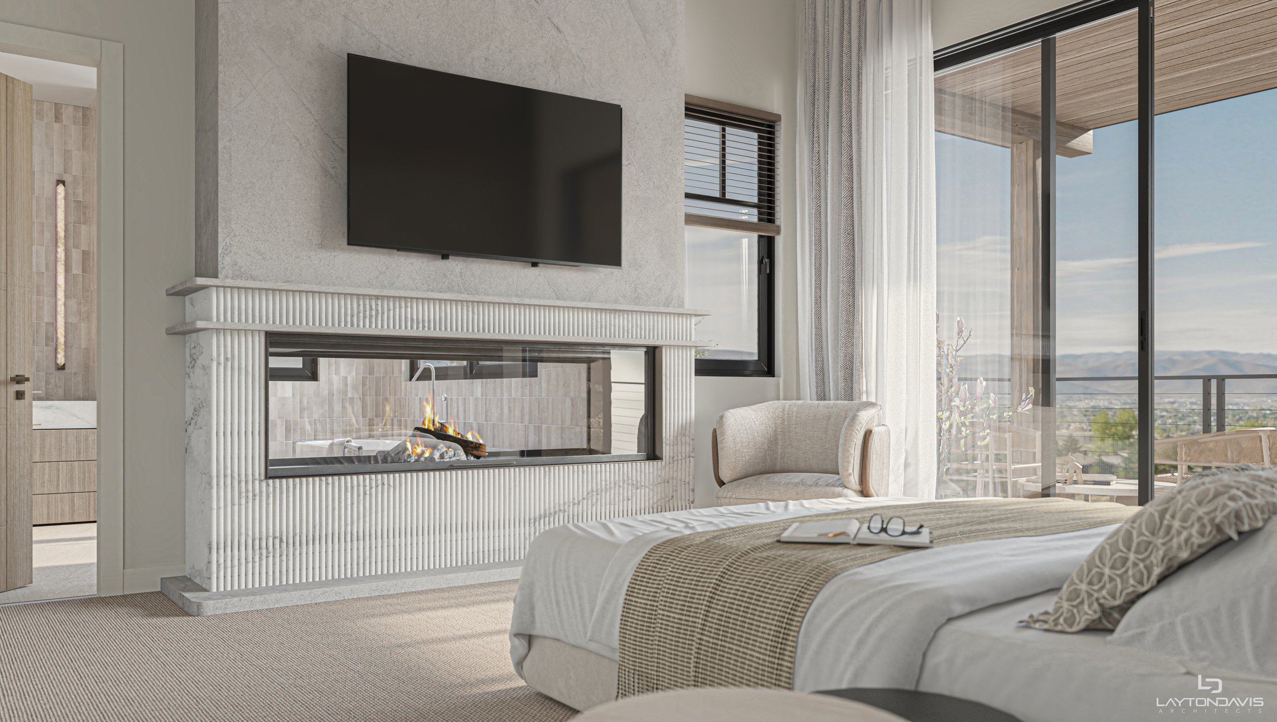 Modern bedroom with a white bed, open book, and eyeglasses on it, a beige armchair near a fireplace with a television mounted above, large windows with curtains, and a view of an outdoor balcony with mountains in the distance.