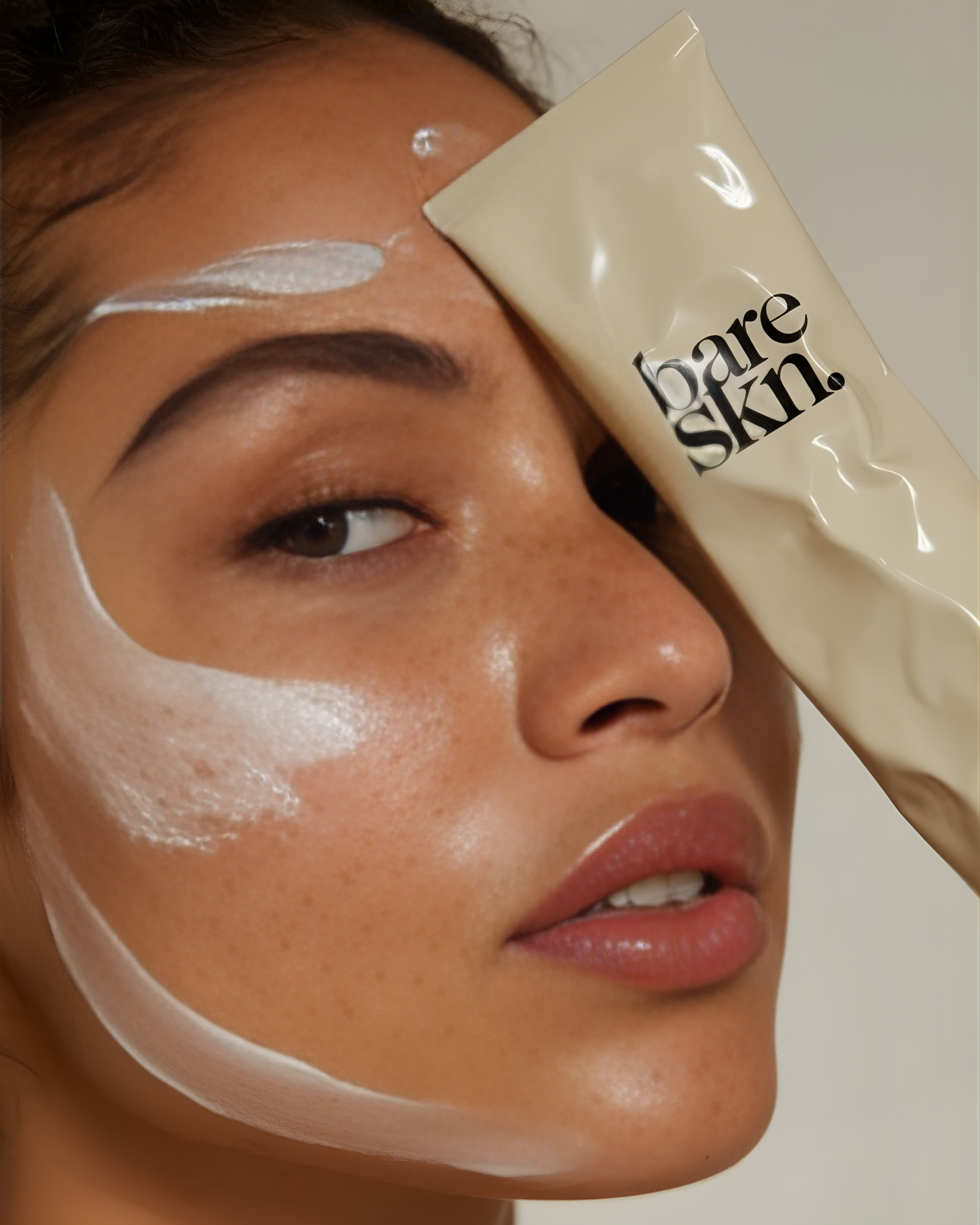 Close-up of a woman's face with a skincare product, labeled 'Dare Skin,' applied to her forehead and cheek, with visible moisturizer on her skin.