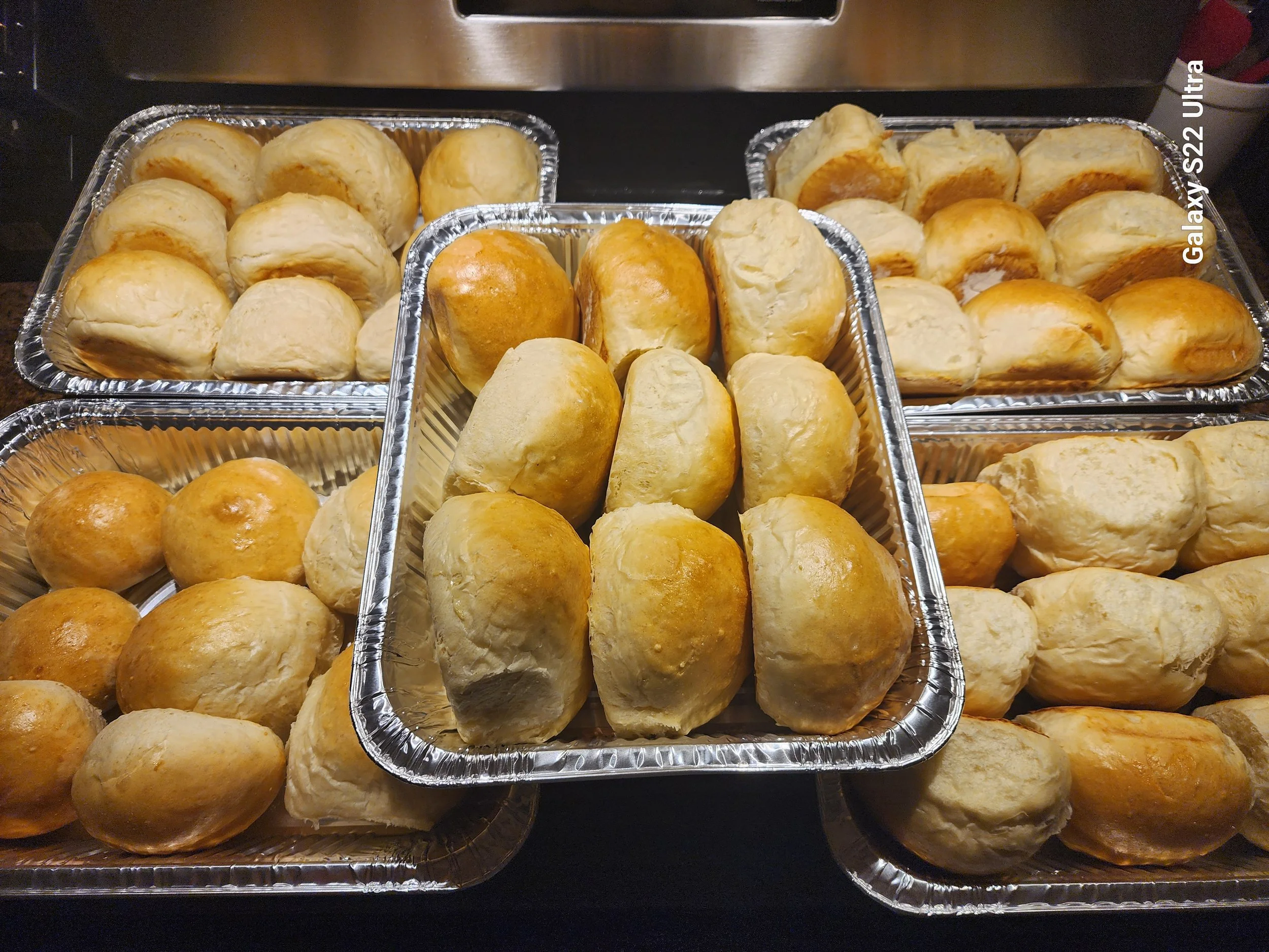 Tray of freshly baked bread rolls, some with golden crust.
