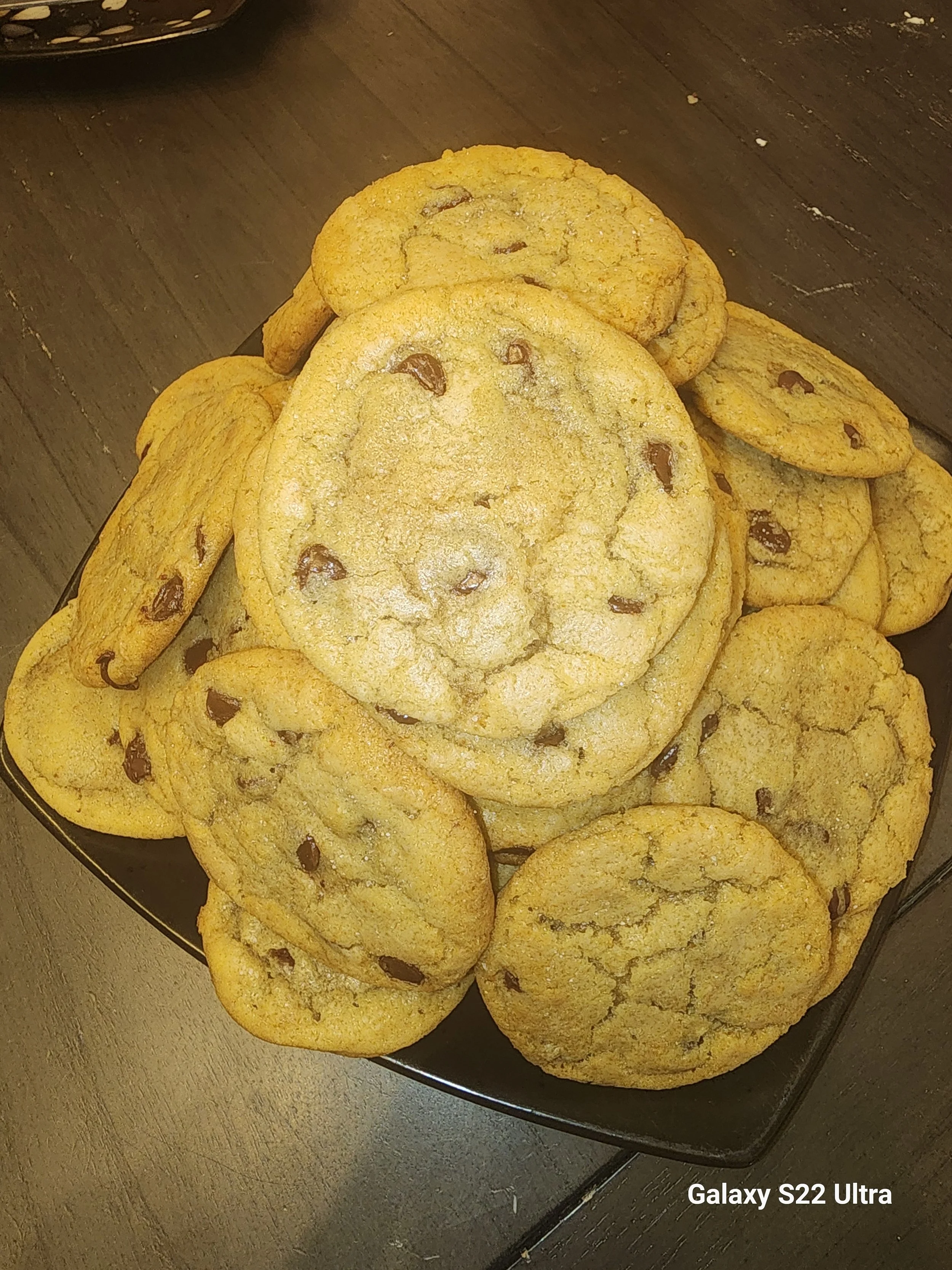 Close-up of a platter of chocolate chip cookies on a wooden table.