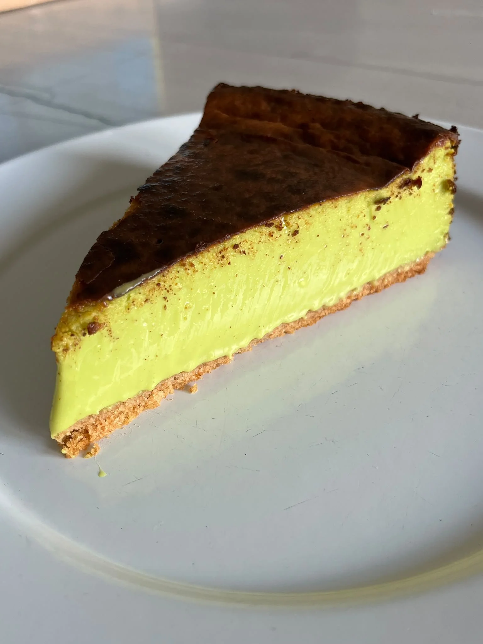 Close-up of a Pistachio Basque Cheesecake slice on a white plate