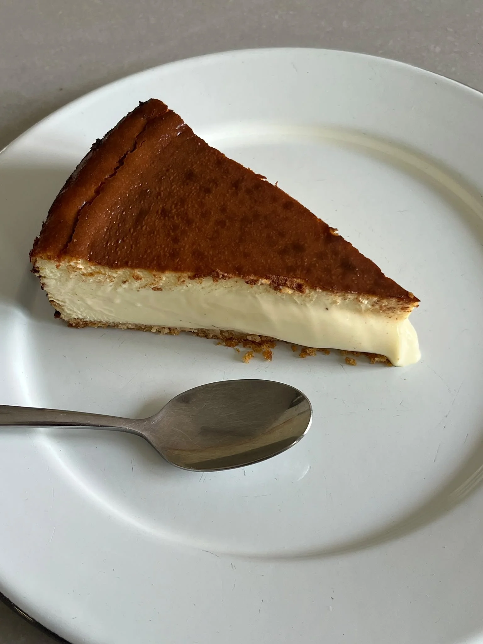 Original Basque Cheesecake slice on a white plate with a spoon
