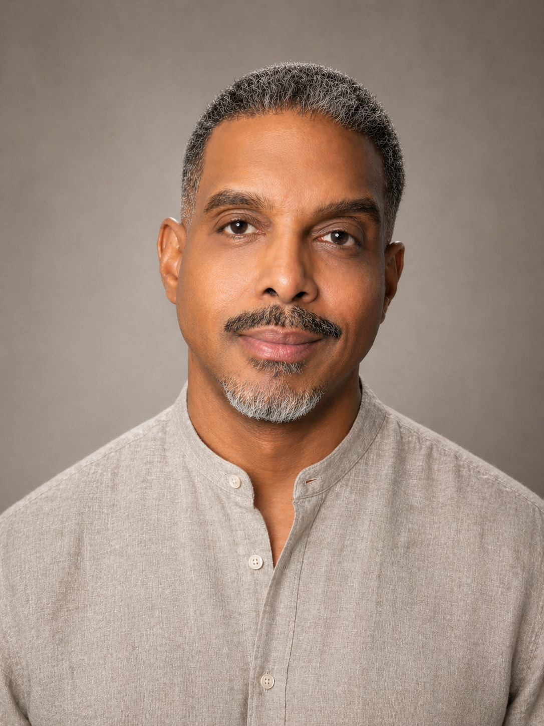 A middle-aged man with short gray hair and a mustache, wearing a light beige collared shirt, looking directly at the camera with a neutral expression.