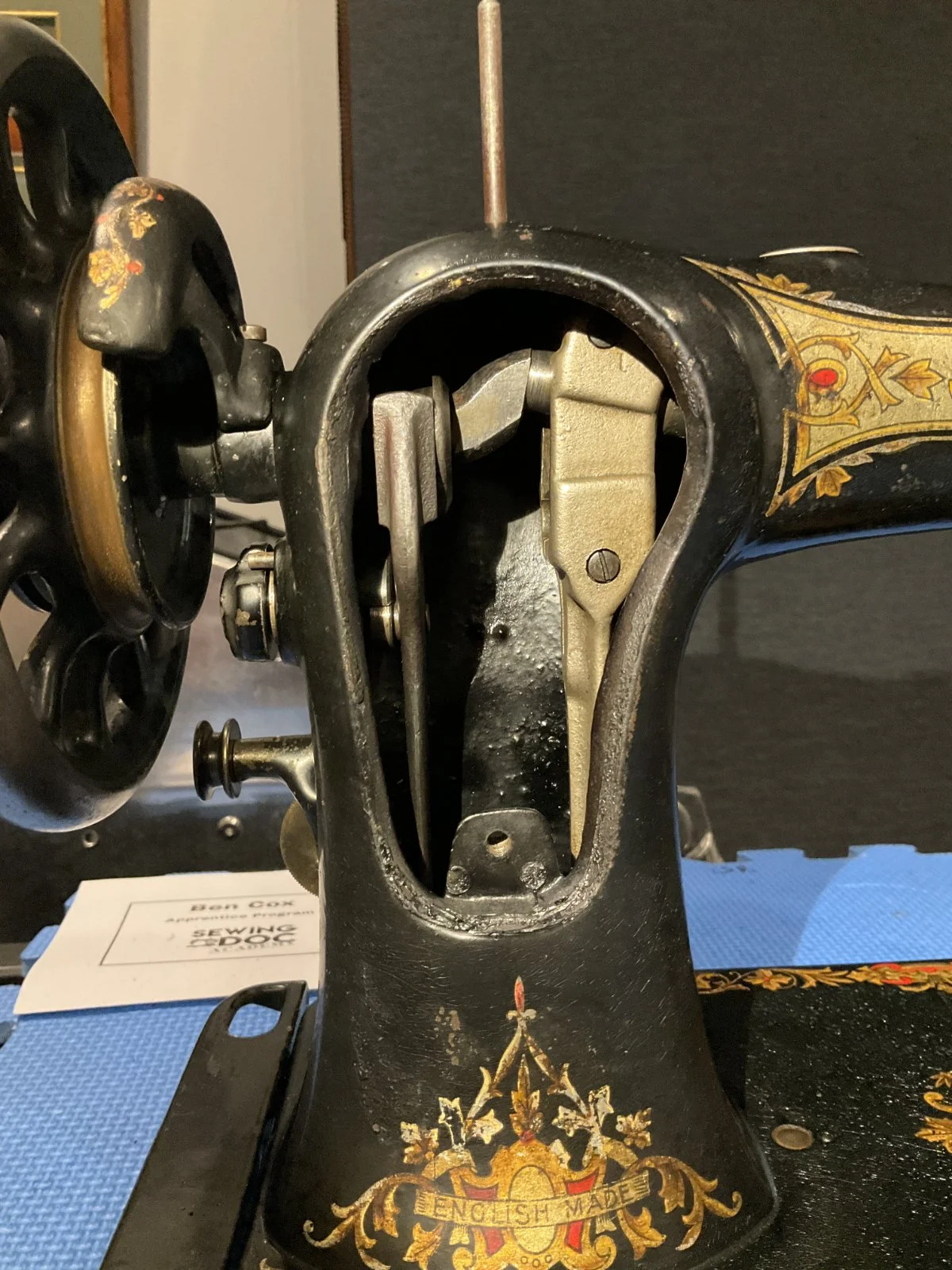 Close-up of an antique Jones sewing machine after restoration, with ornate gold and red floral patterns and the words 'English Made' on its base.