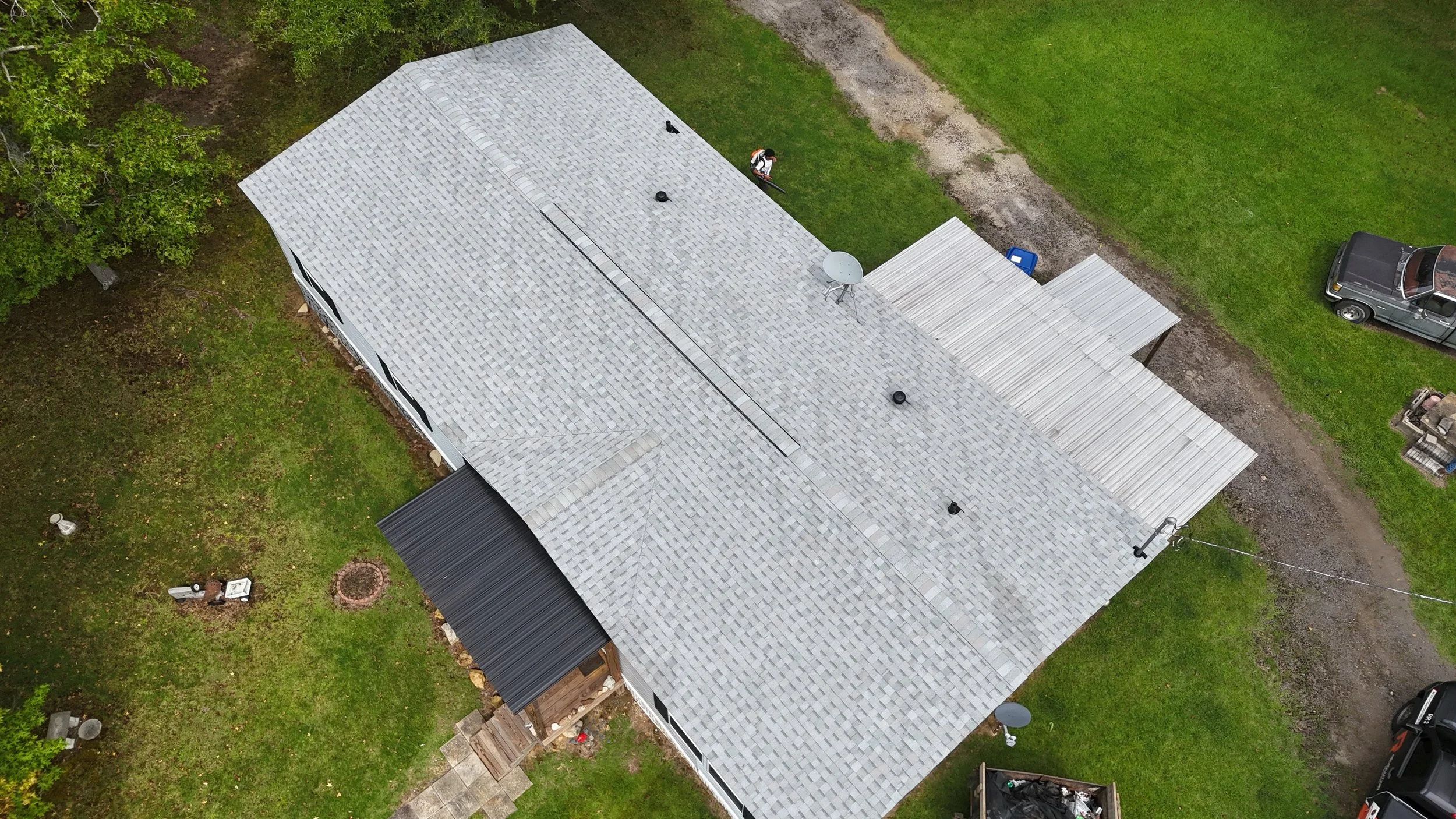An aerial view of a house with a gray shingled roof and a small covered porch where Revolution Roofing installed new shingles.