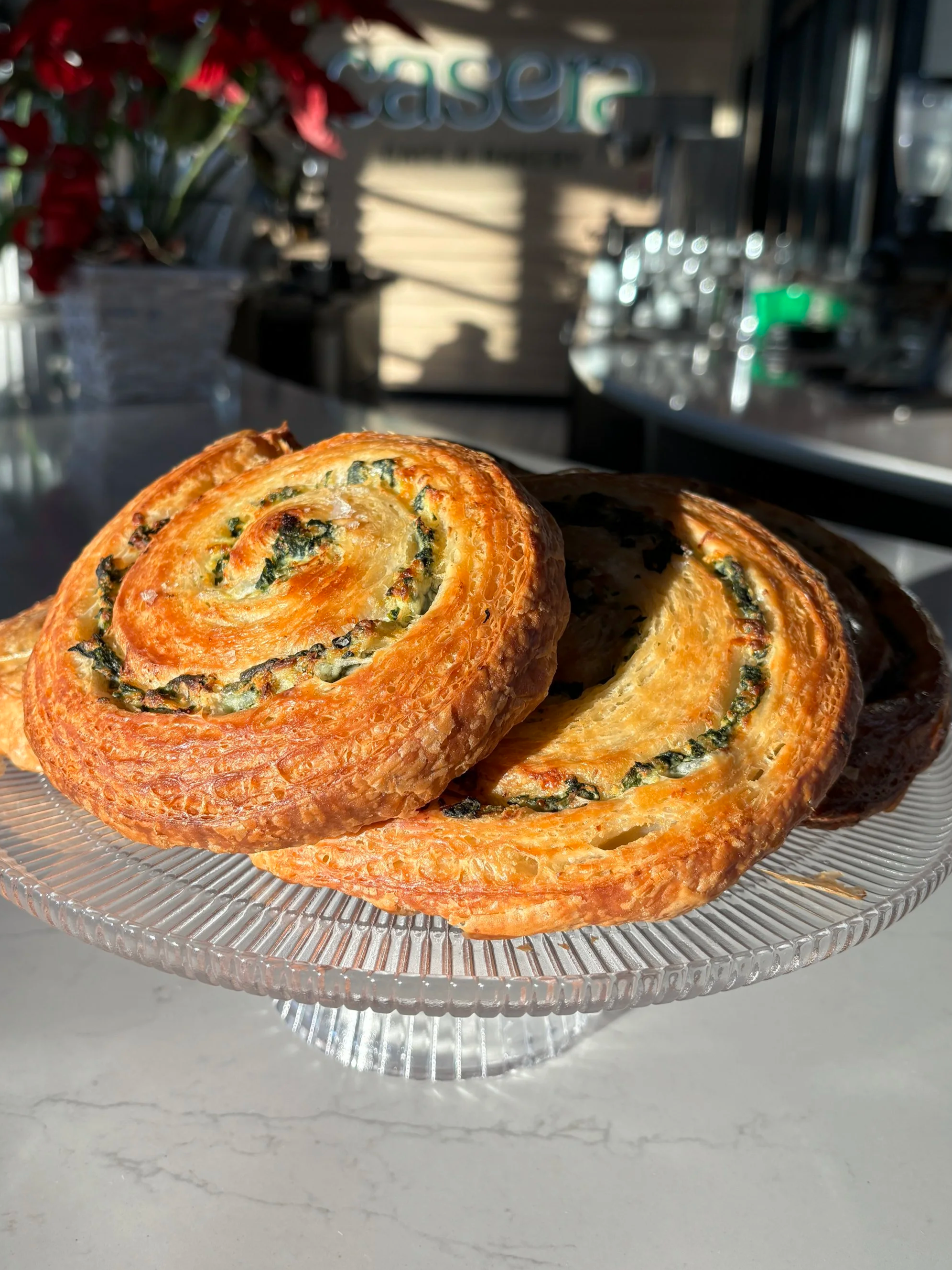 Two slices of spinach and cheese puff pastry on a glass cake stand.
