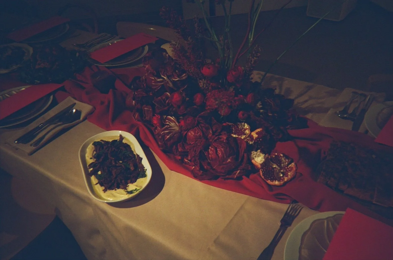 A decorated table for a celebration with floral arrangements, a plate of food, and place settings with silverware.
